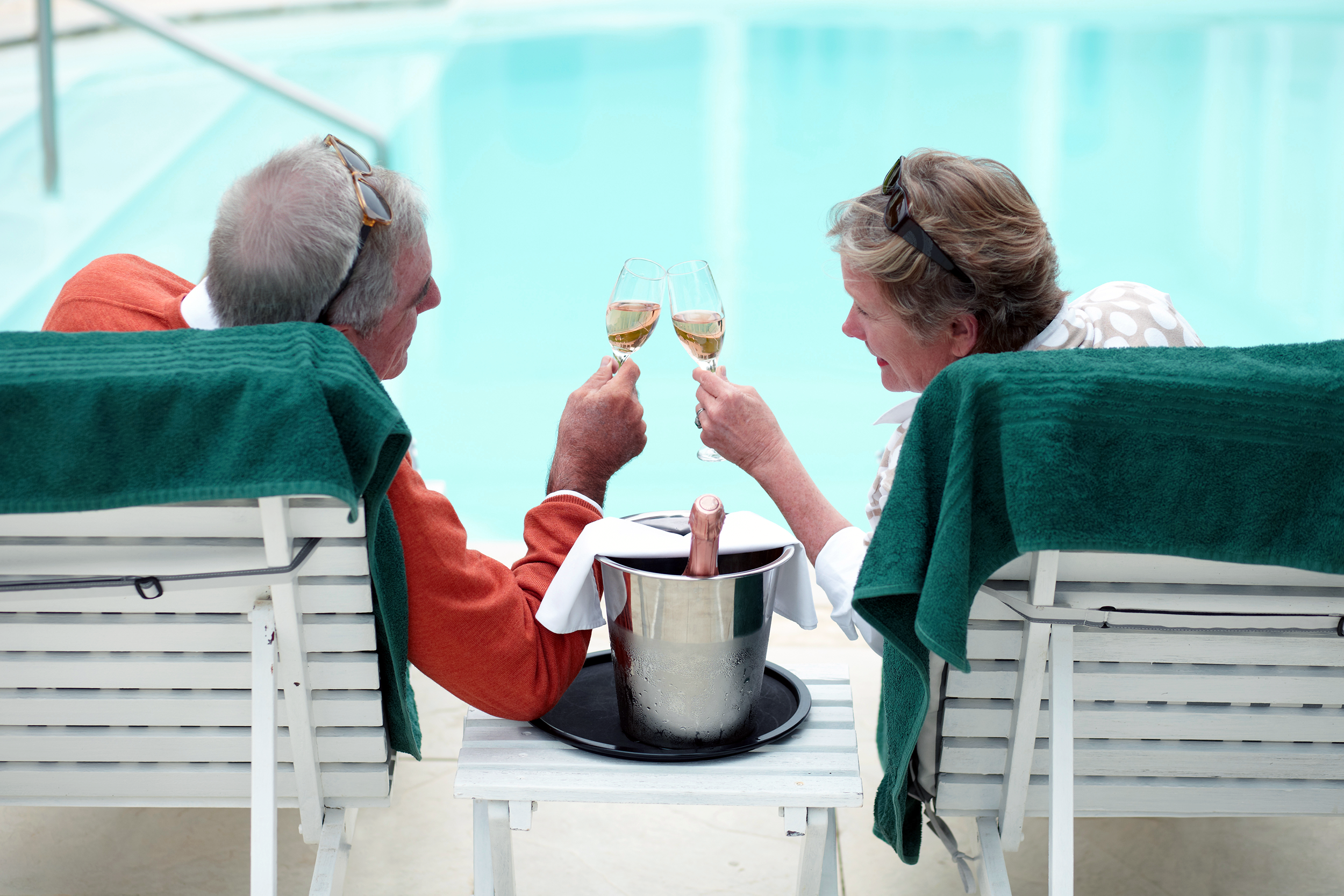 Senior couple lounging by the pool with champagne