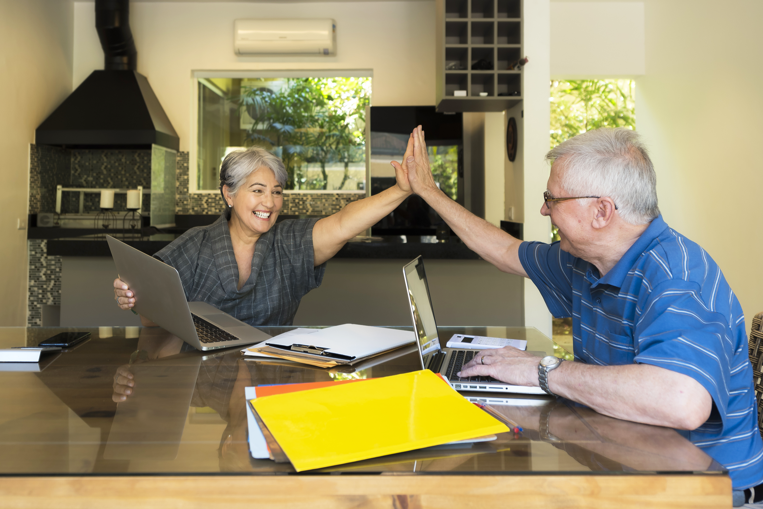 Senior couple high-fiving and doing taxes