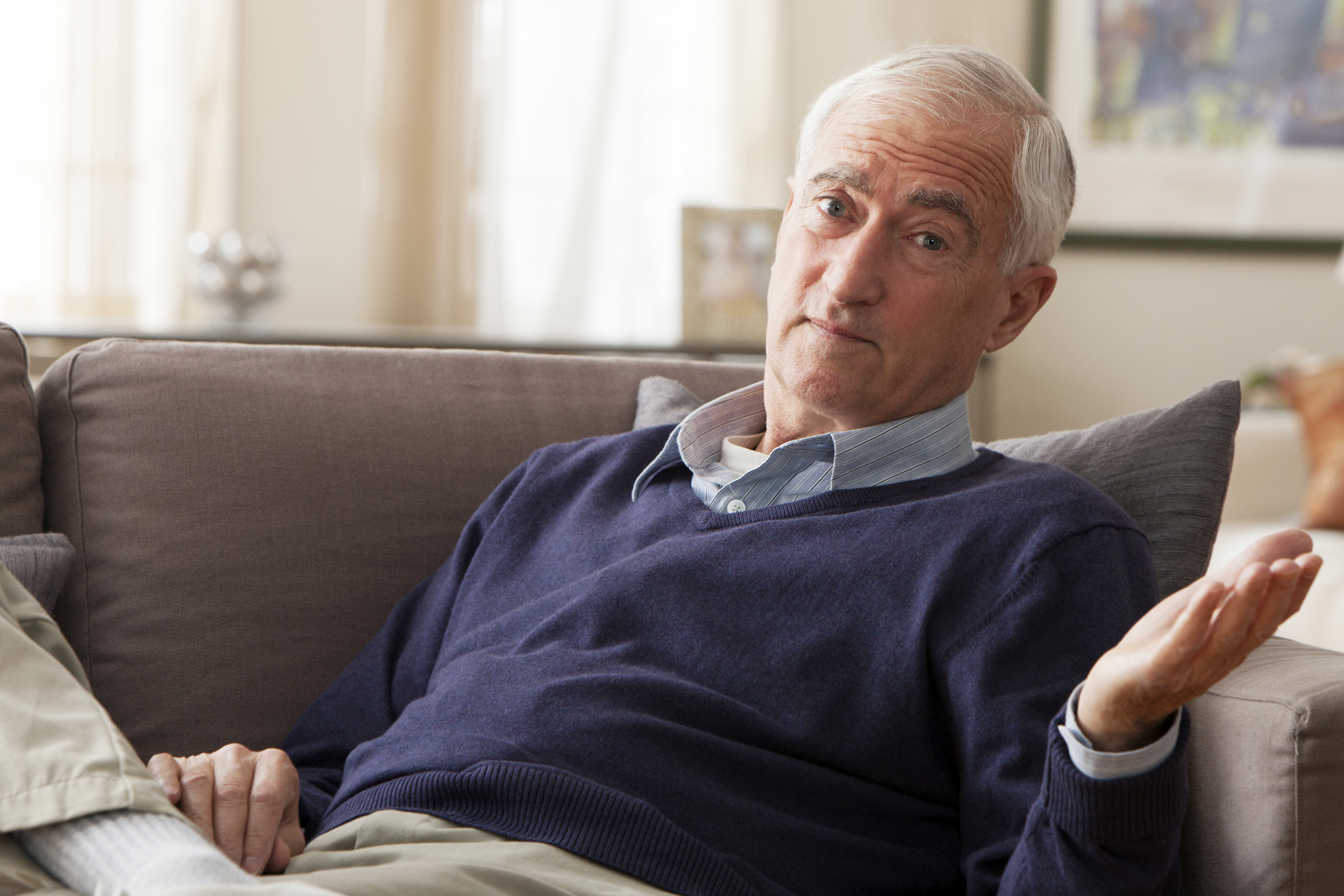 Senior man shrugging on his couch