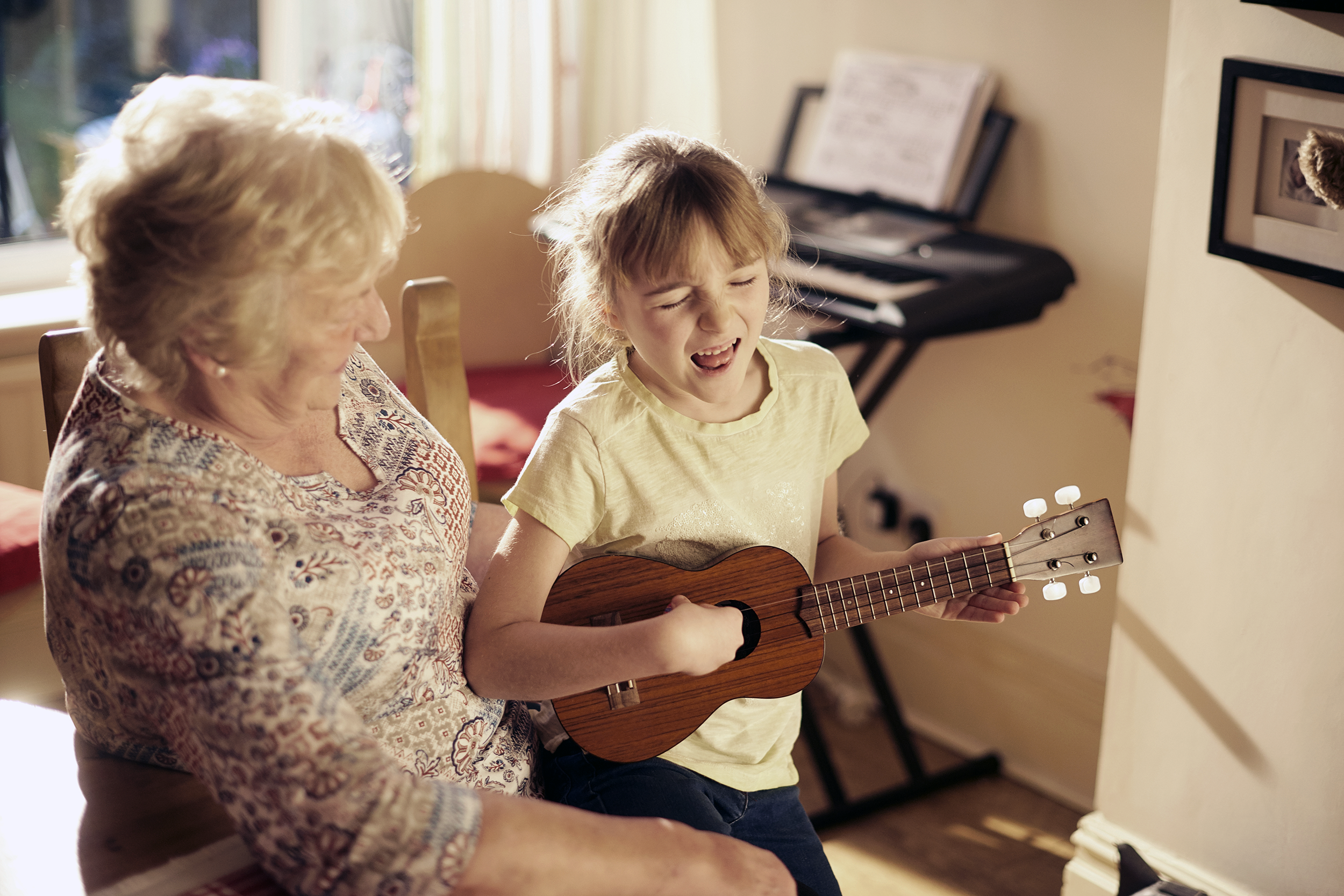 Grandmother listening to her granddaughter play the guitar