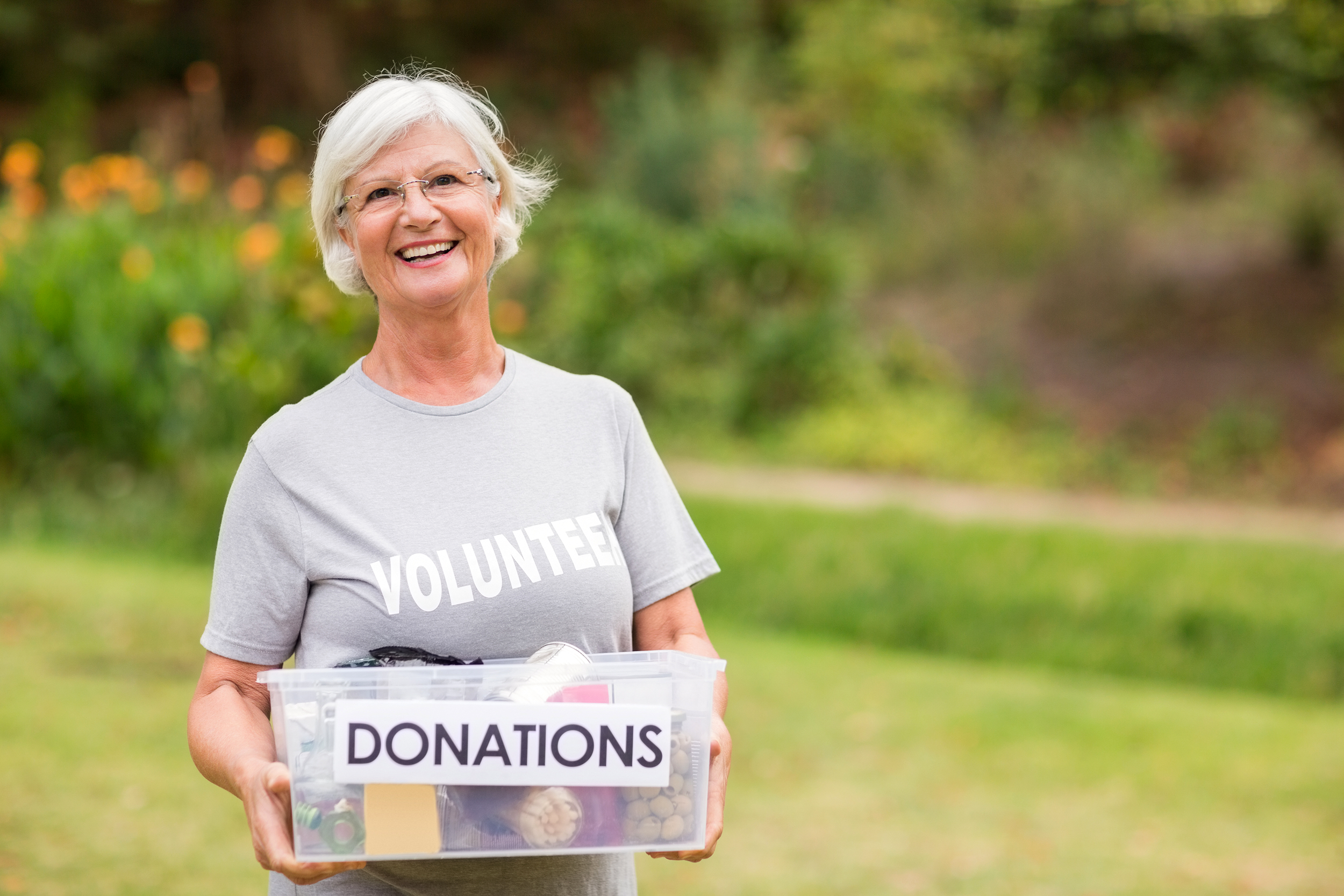 Senior woman volunteering outside with a donation box