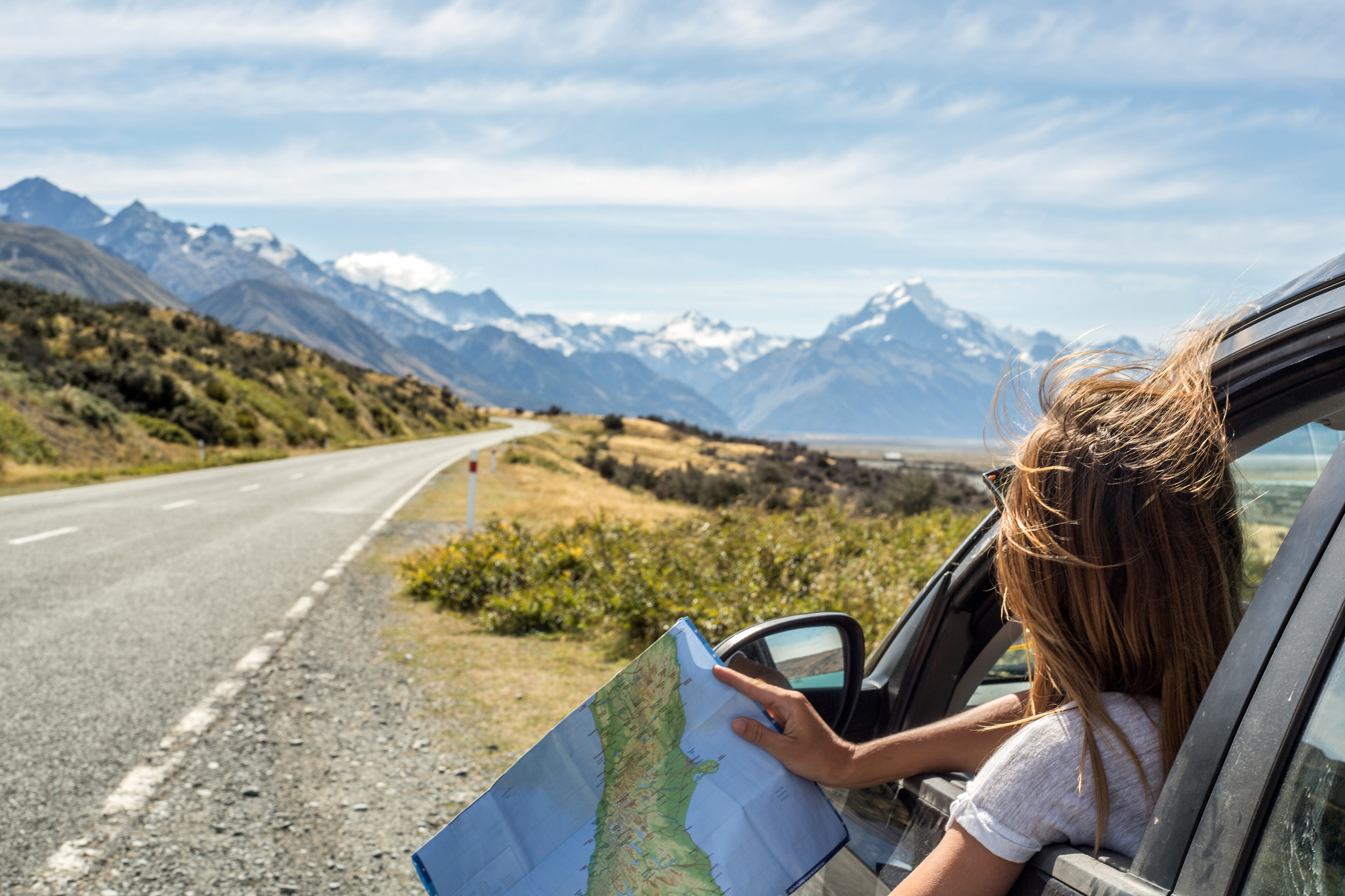 Woman with a map looking out of her window at a mountain range