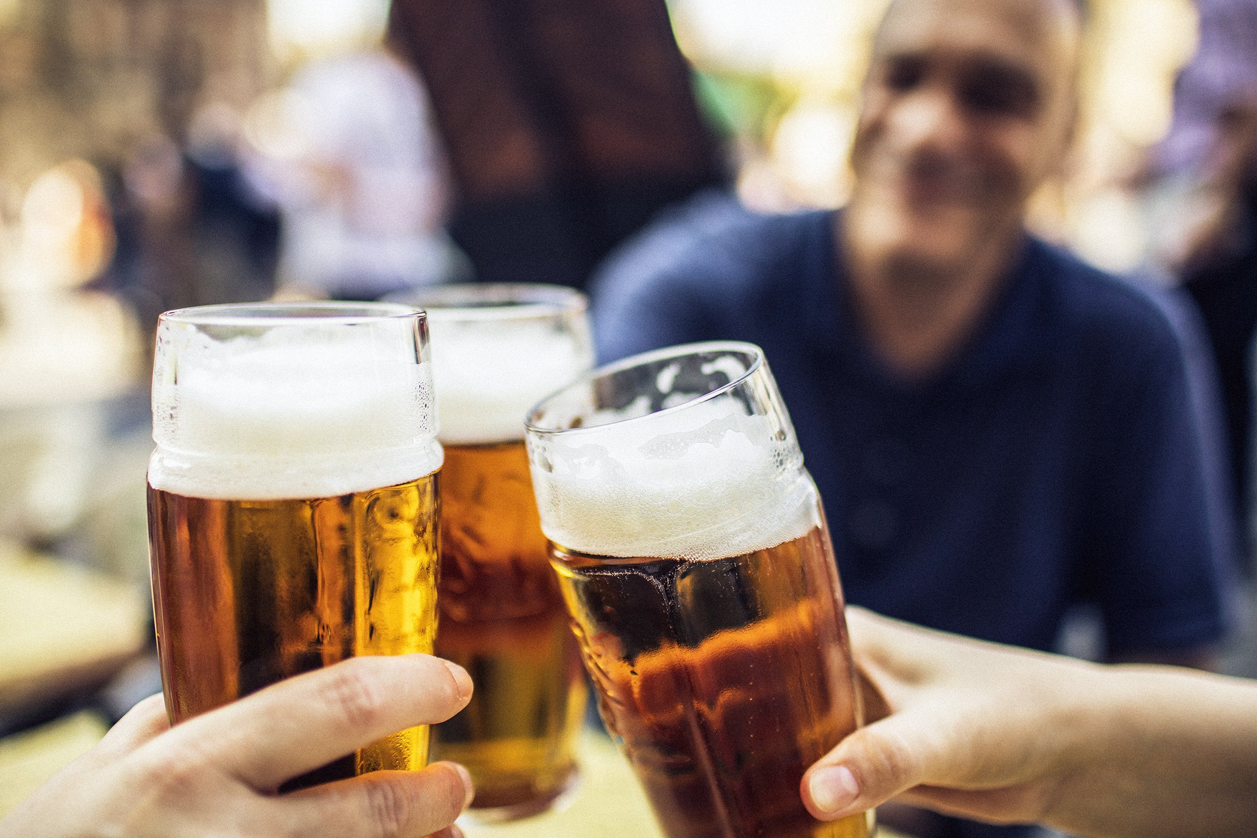 three friends cheering on good news with glasses of pilsner beer