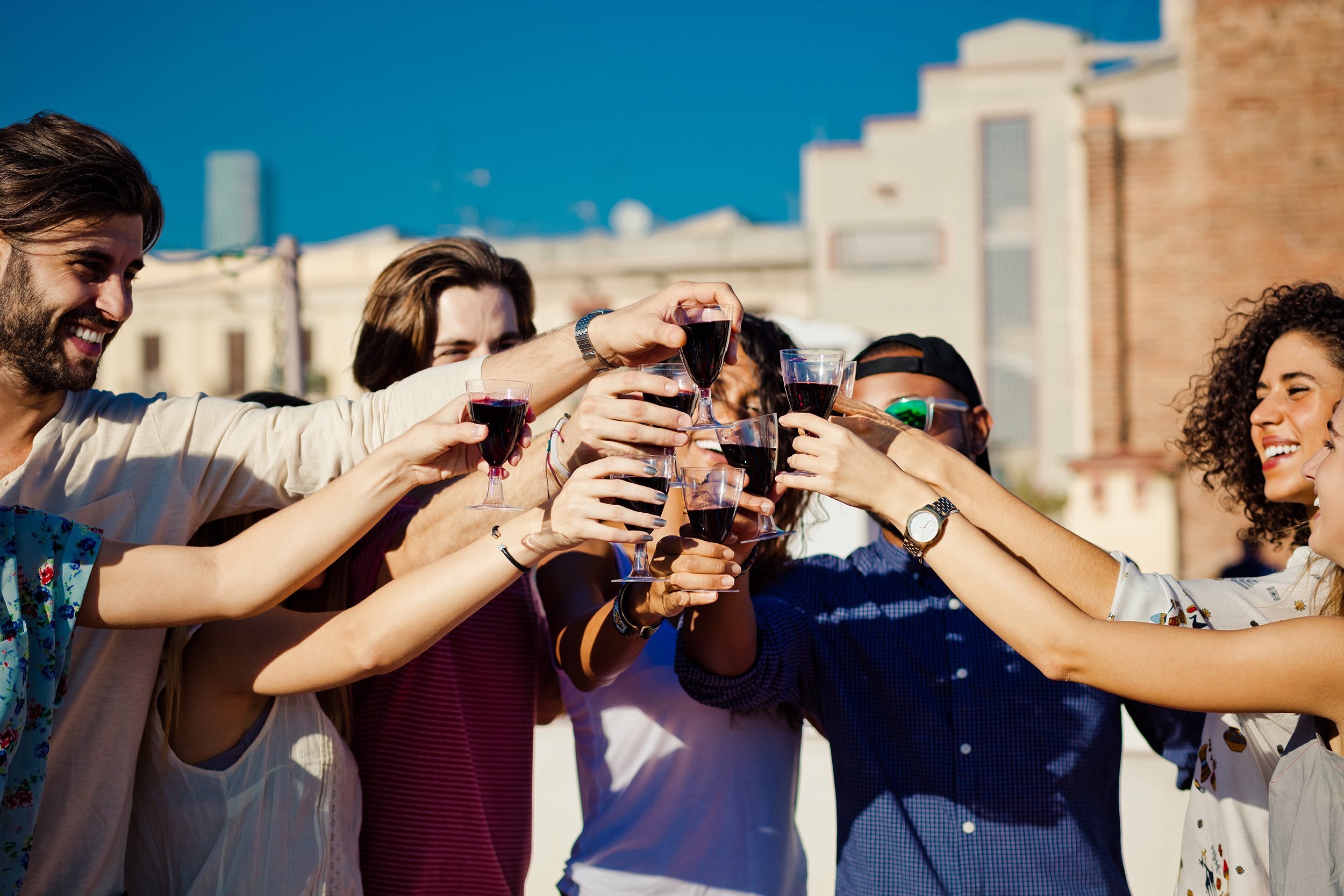 happy friends drinking wine at rooftop party