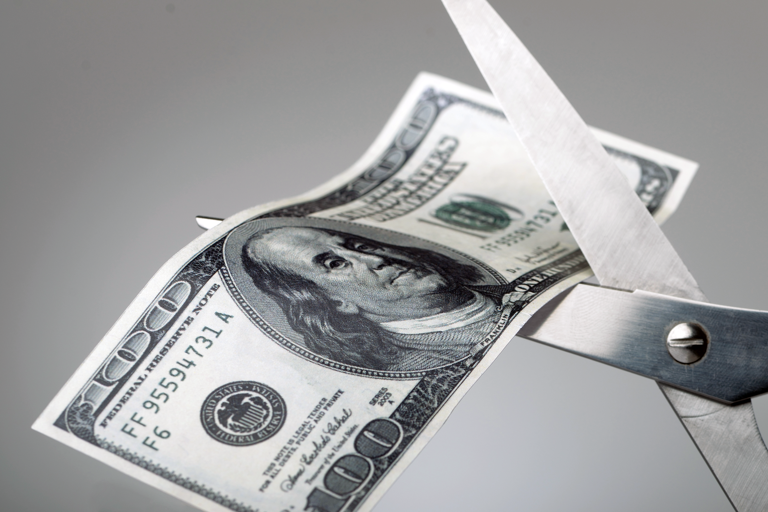Scissors cutting a $100 bill