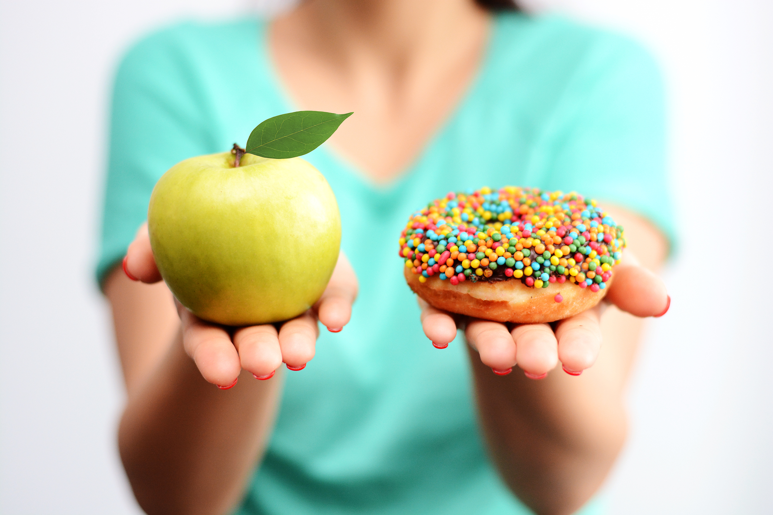 Woman with hands out holding an apple and a donut