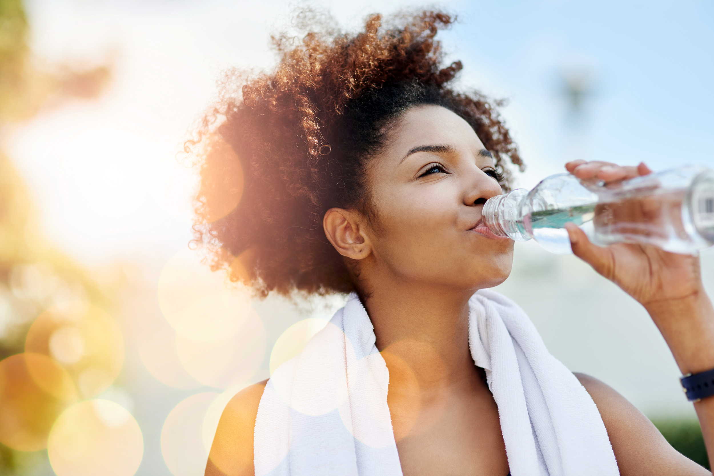 Woman wearing a towel around her neck and drinking water