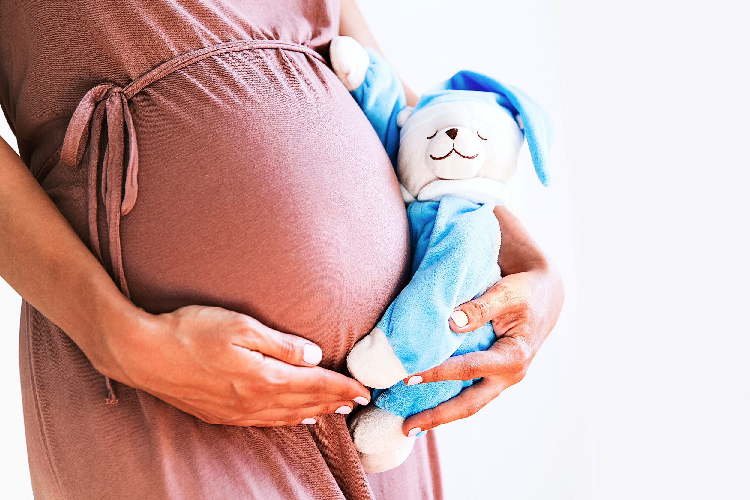 Pregnant woman holding a stuffed toy next to her belly