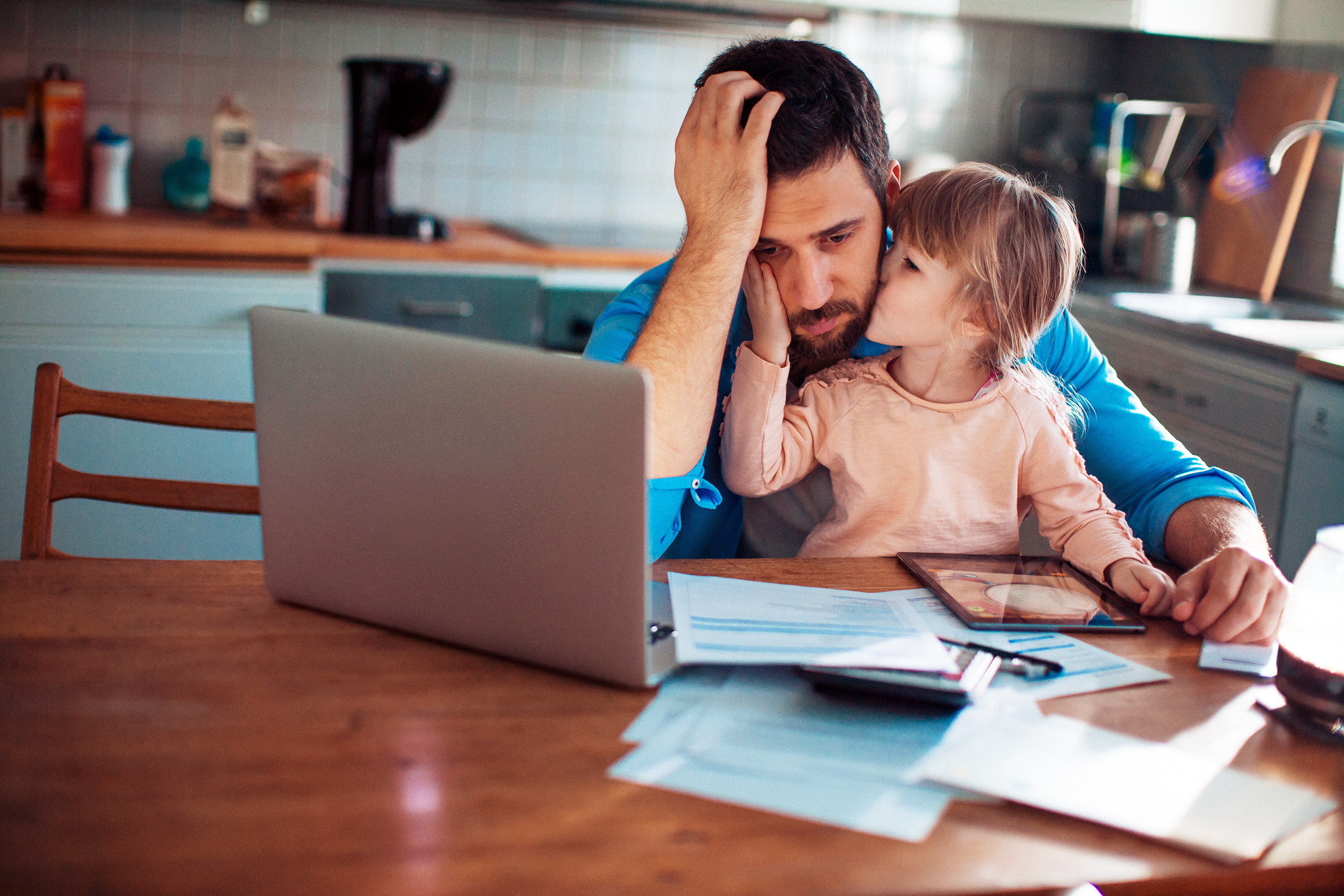 Stressed out Dad doing finances holding his daughter