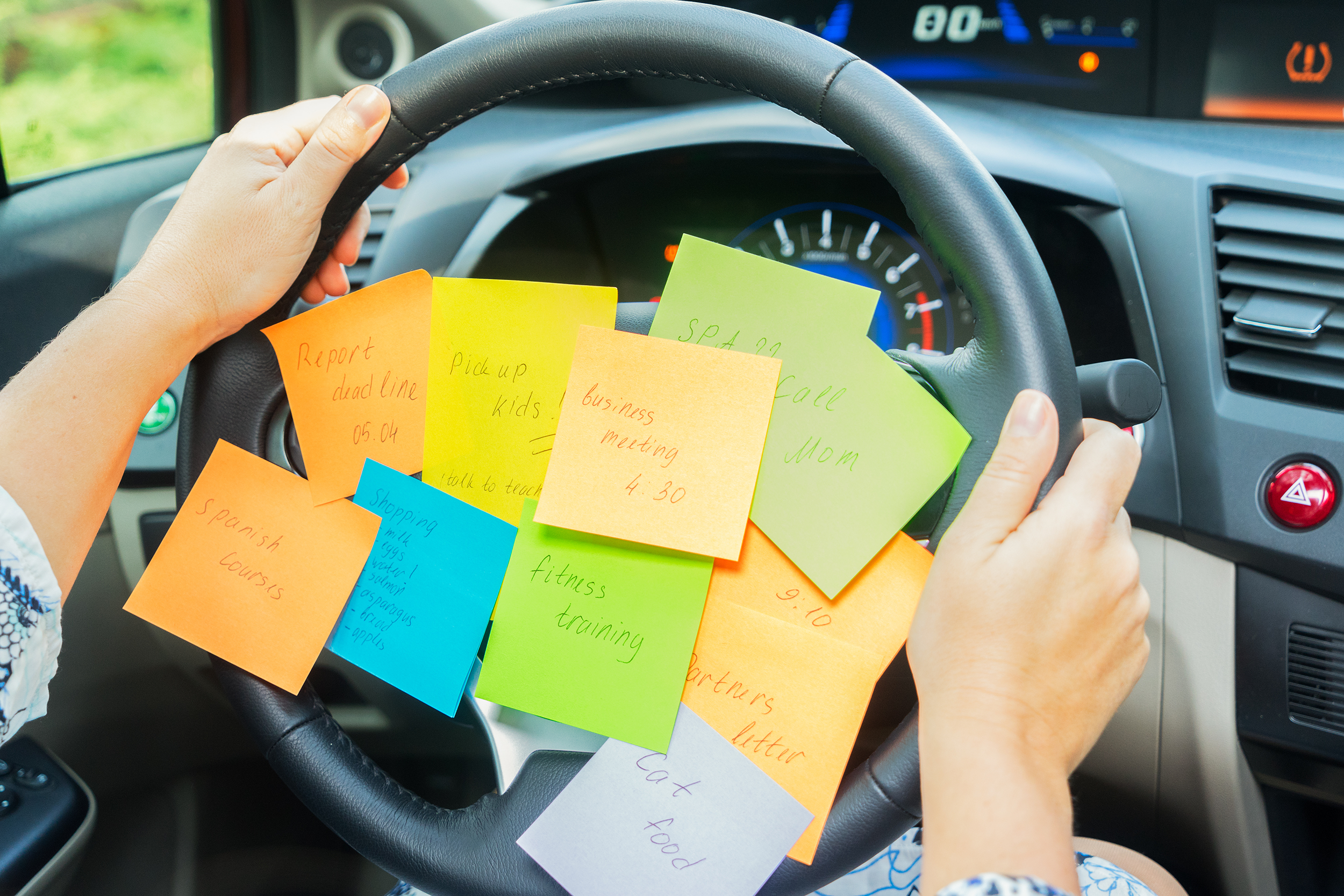 Steering wheel in a car full of sticky notes with things to do