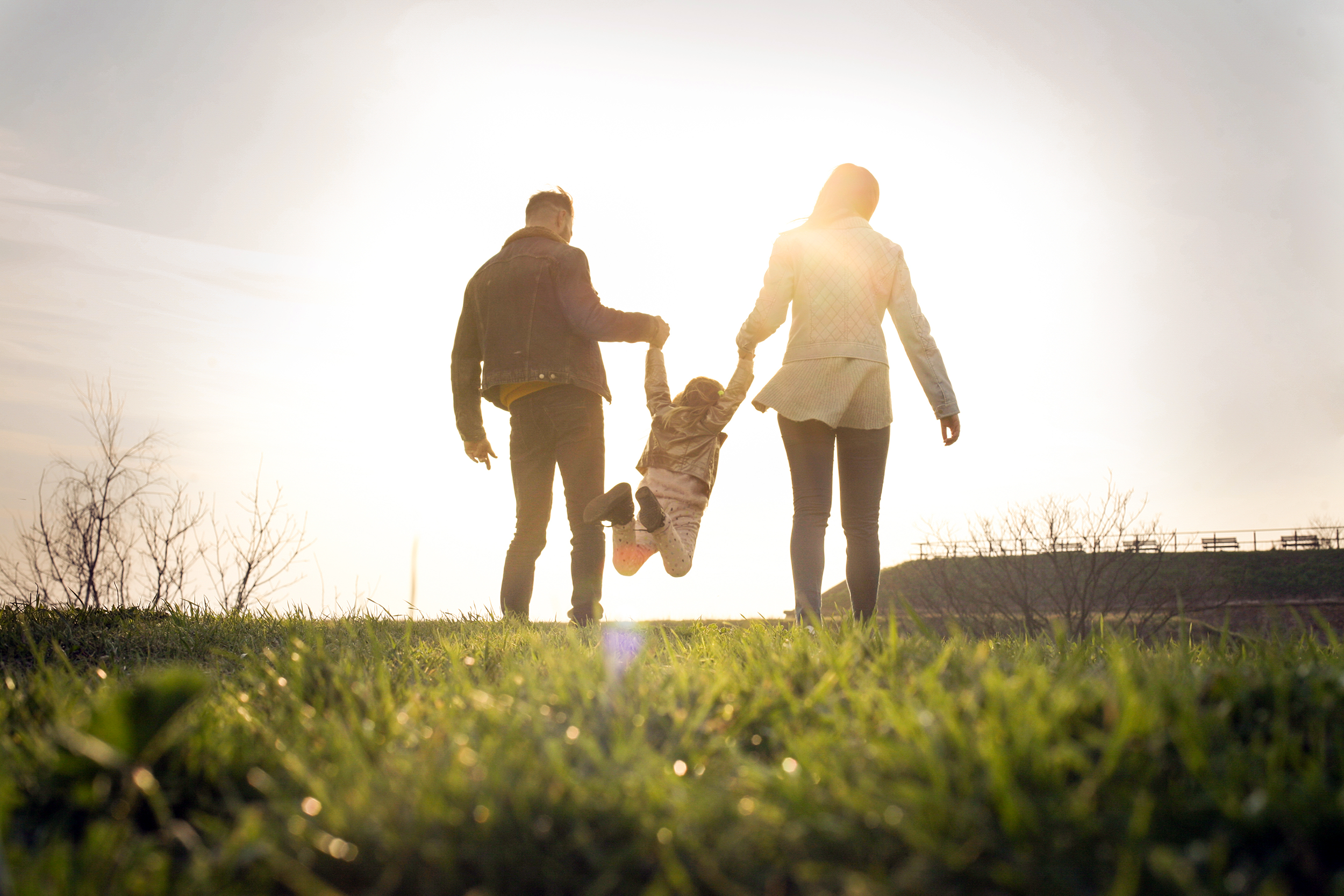 Couple walking with their child swinging by his arms