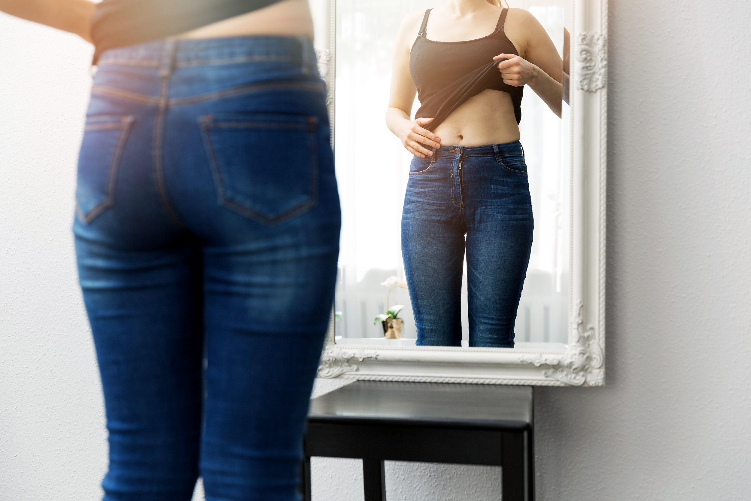 Woman looking at her body in the mirror
