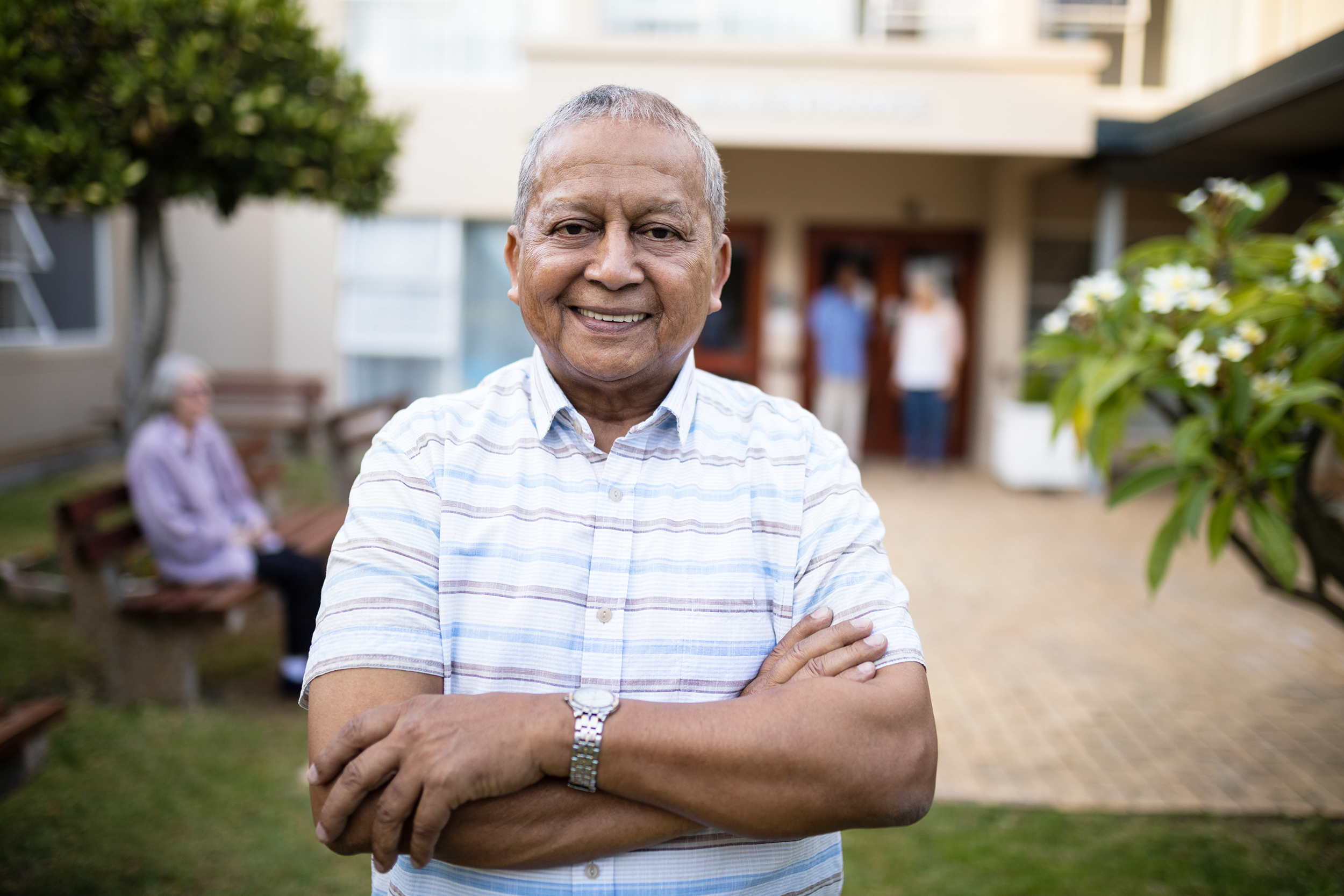 Happy senior man standing in front of senior living community
