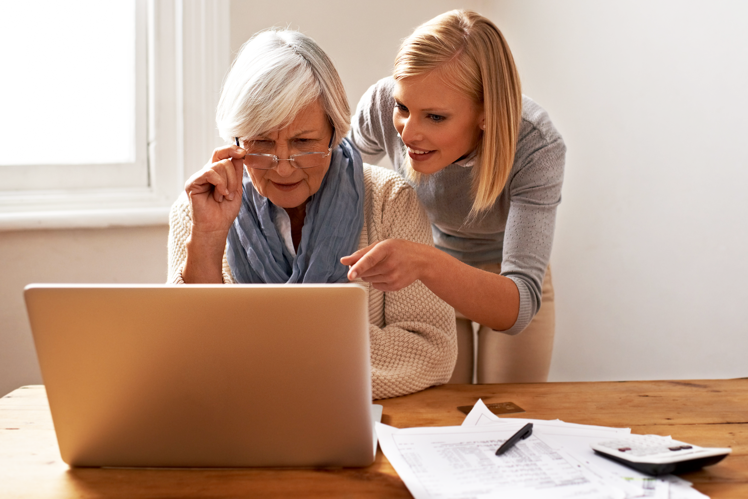 Young woman assisting a senior woman on her computer with finances