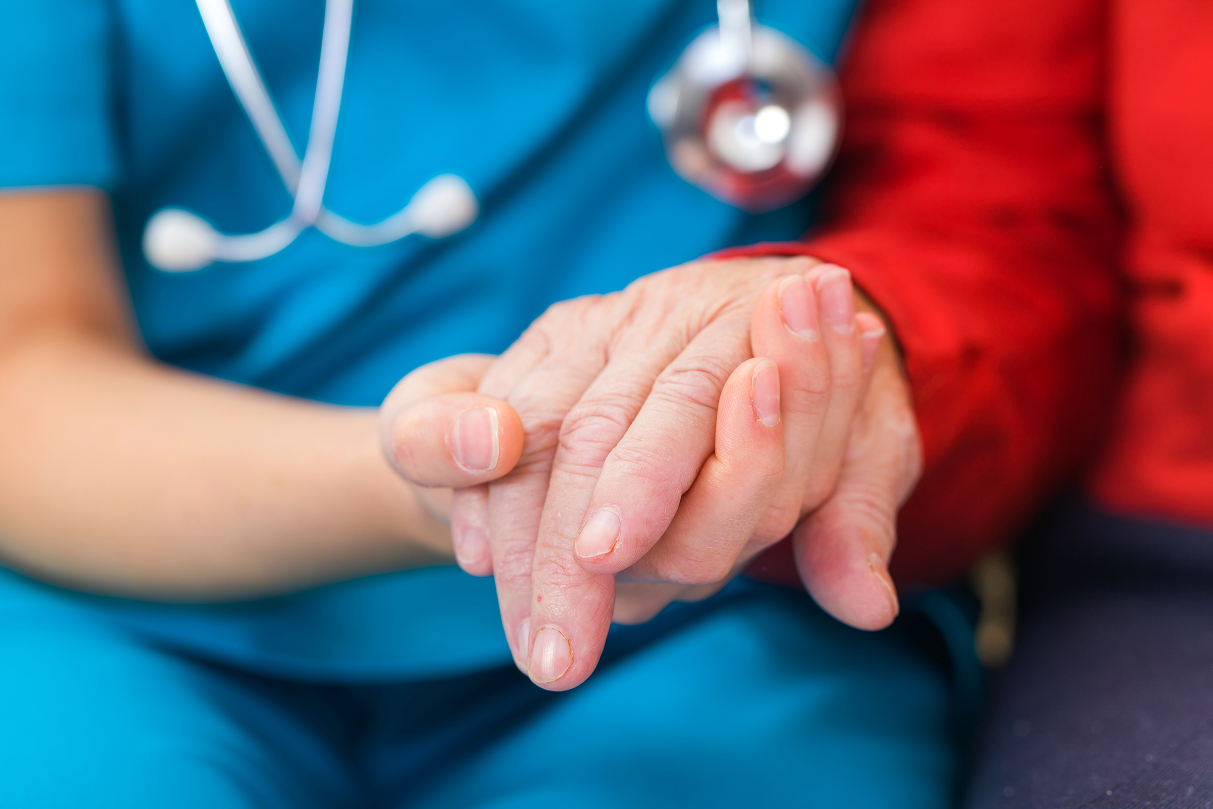 Closeup of nurse holding a senior woman's hand