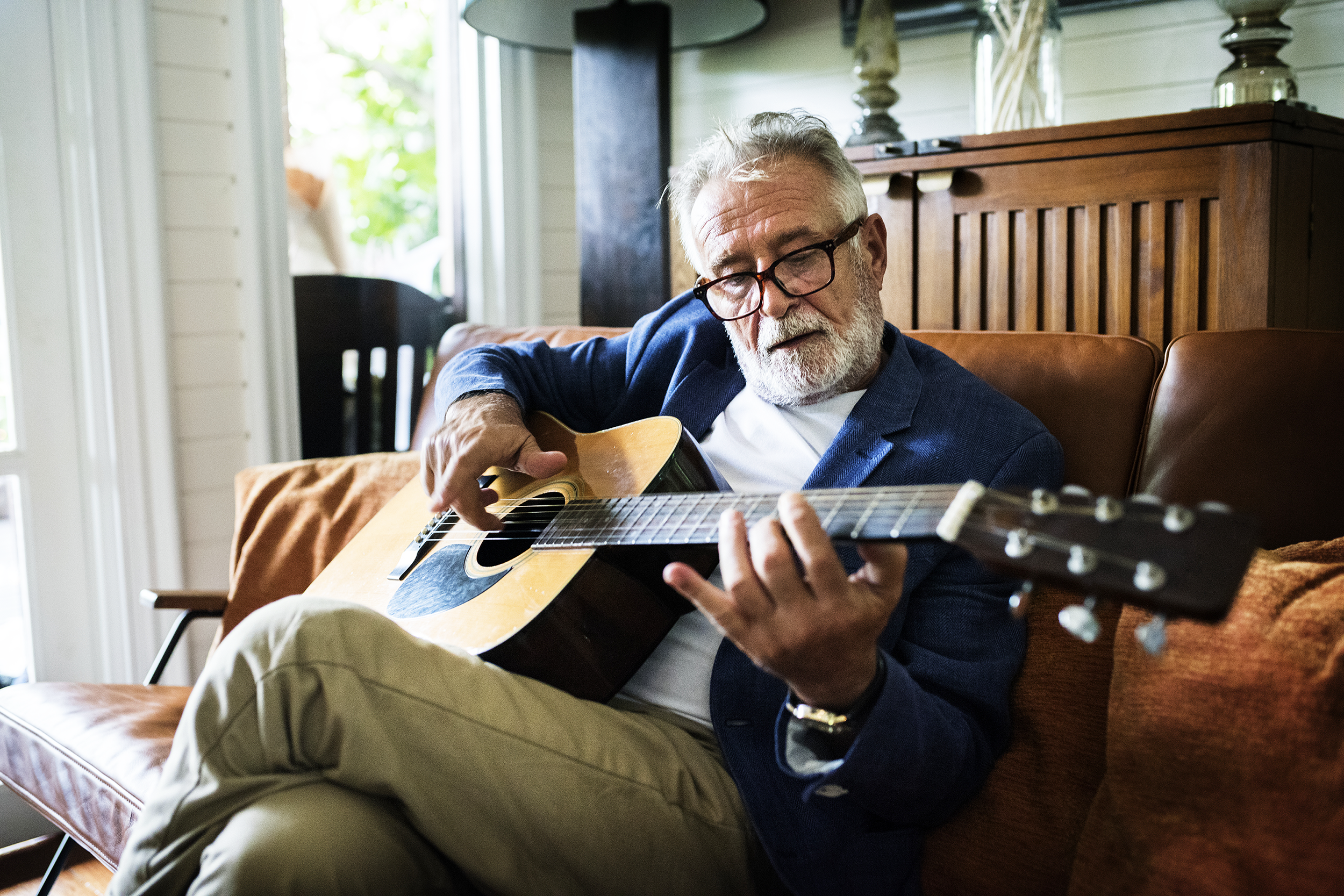 Senior man playing guitar on the couch