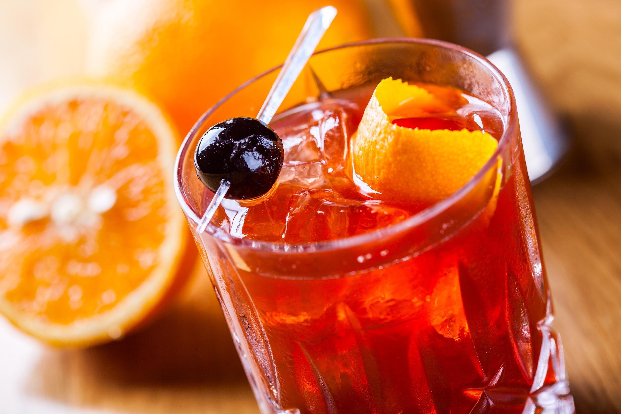 old fashioned cocktail with orange slices in the background