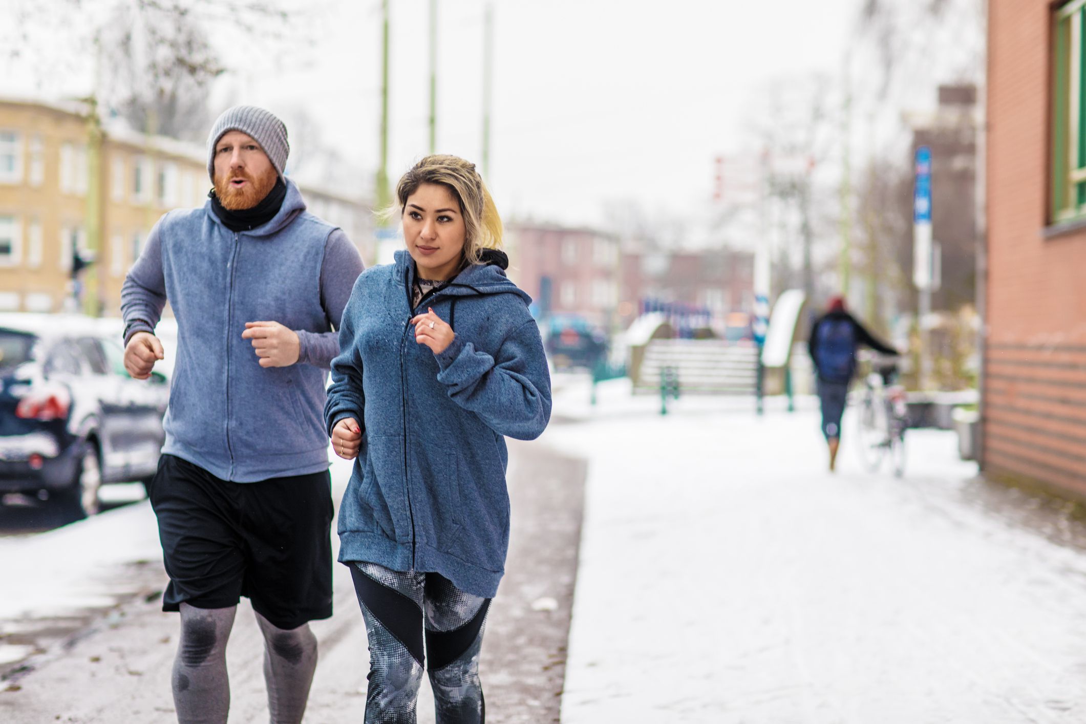 Male personal trainer coaching beautiful woman during an outdoor jogging session in the bad weather