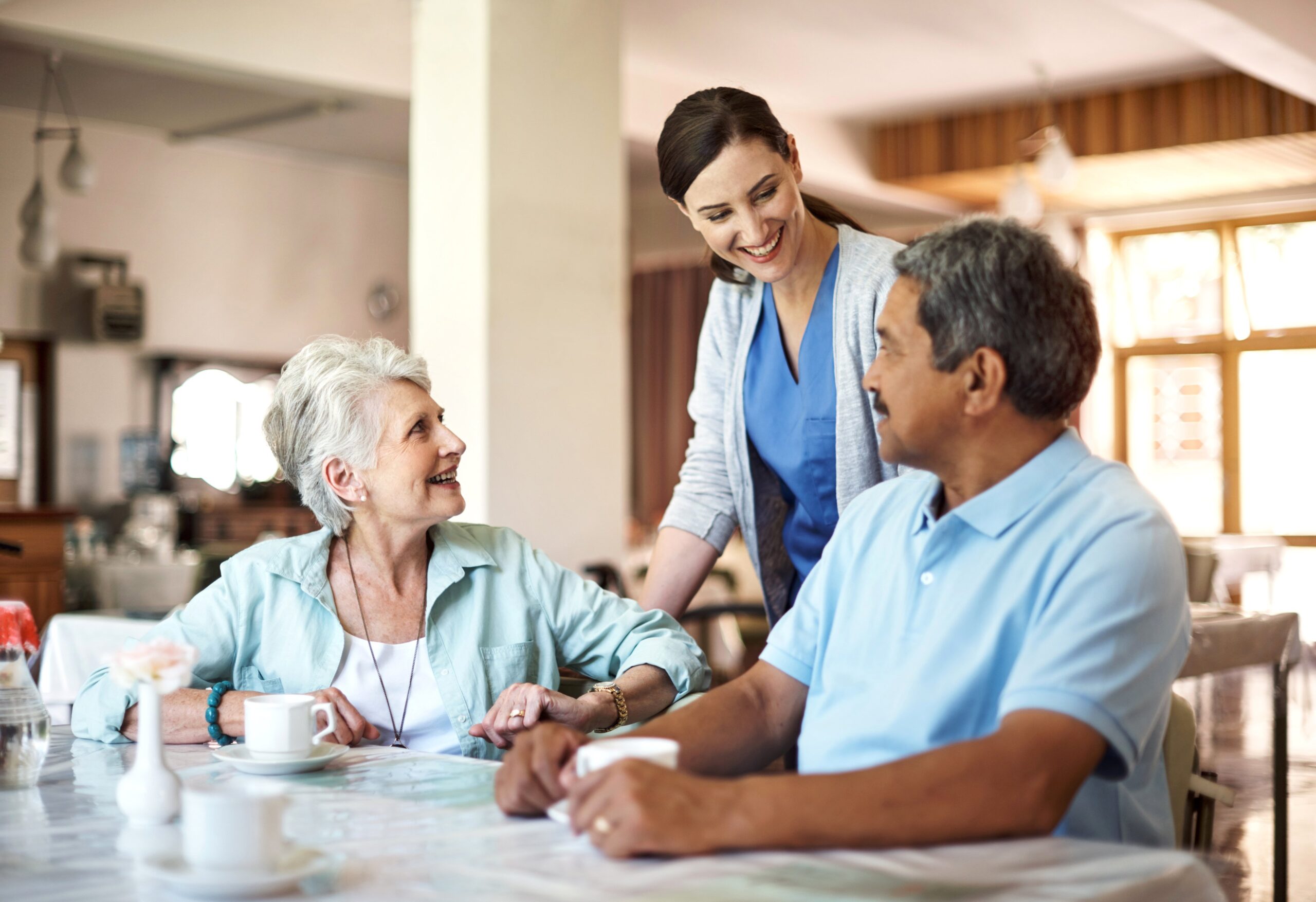 Nursing home attendant checking in on an elderly man and woman