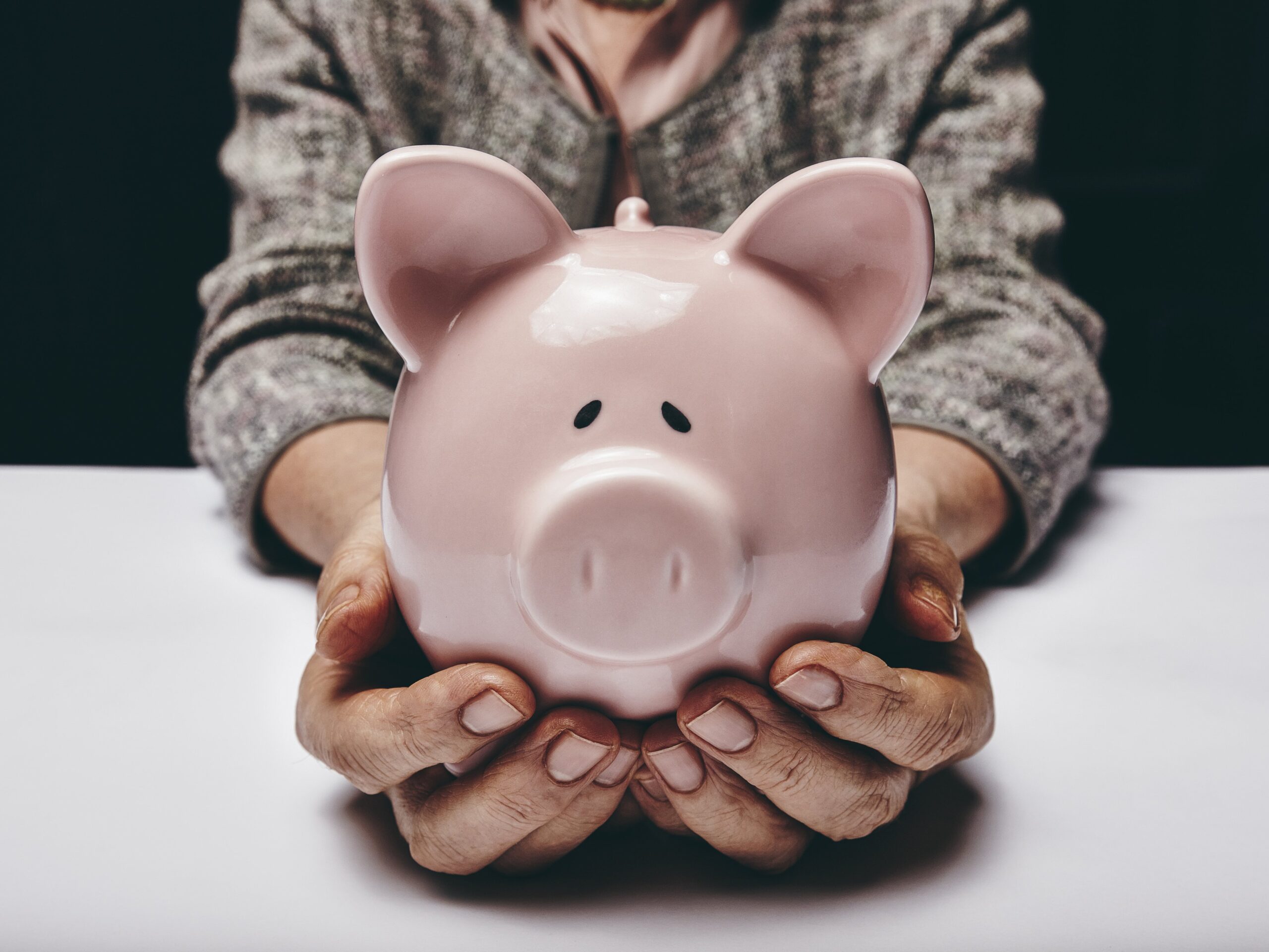 elderly woman holding piggy bank in both hands