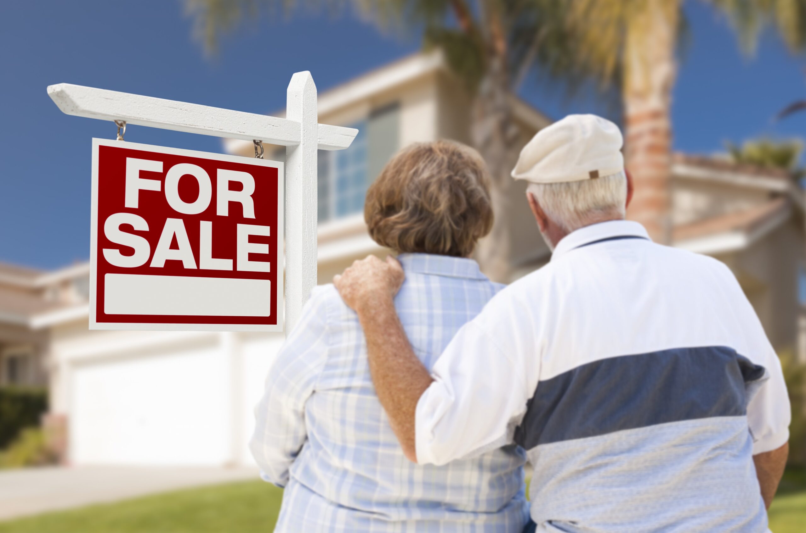 an elderly couple, backs to the camera, staring at their house which they've just sold