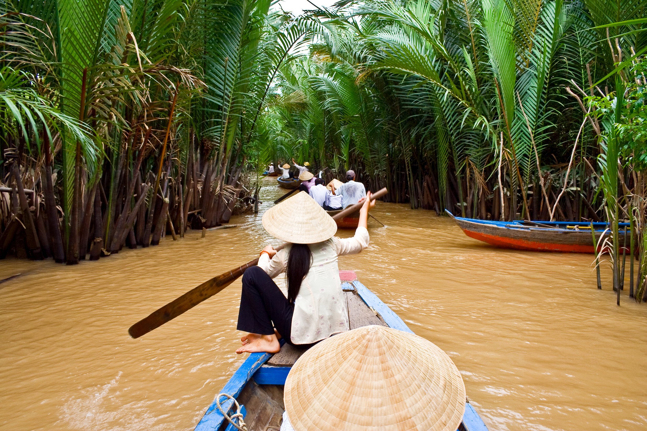 boats in a line rowing down the Mekong river