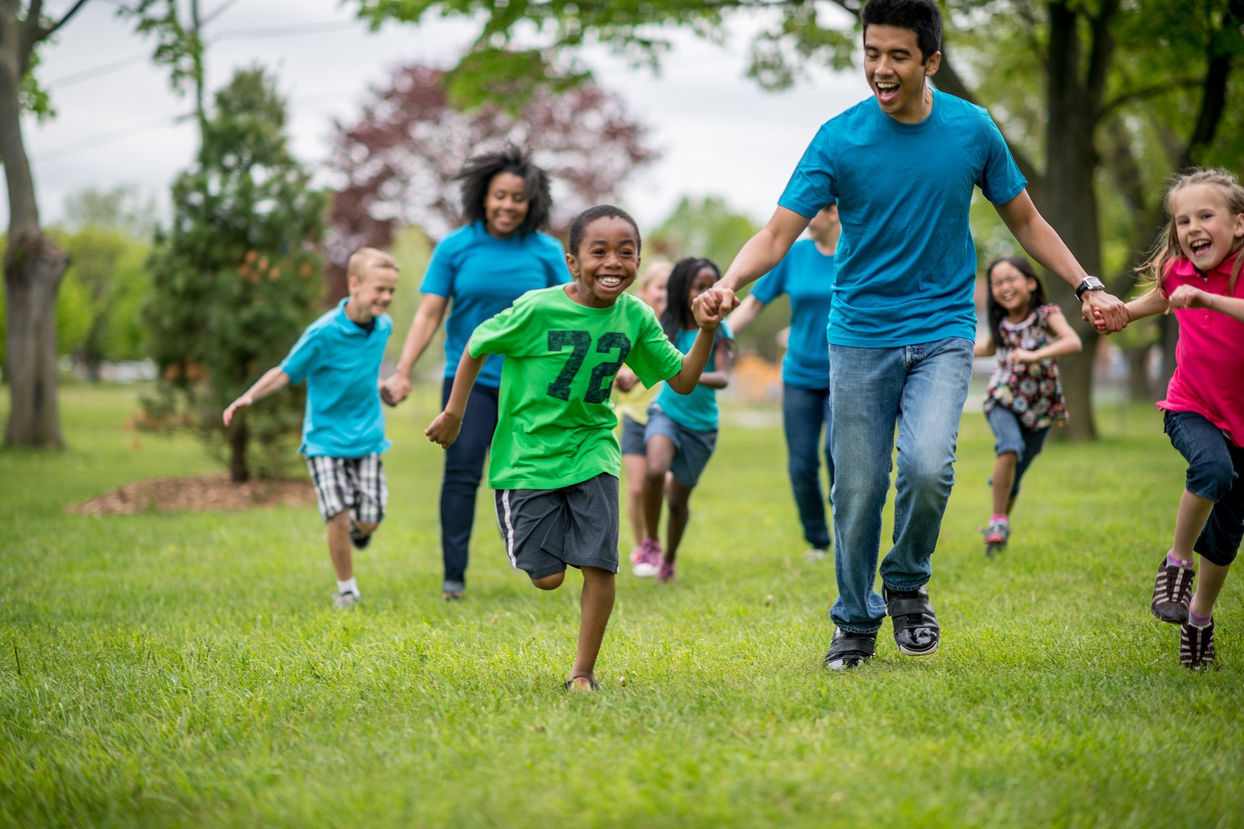 diverse group of kids running outside at day camp