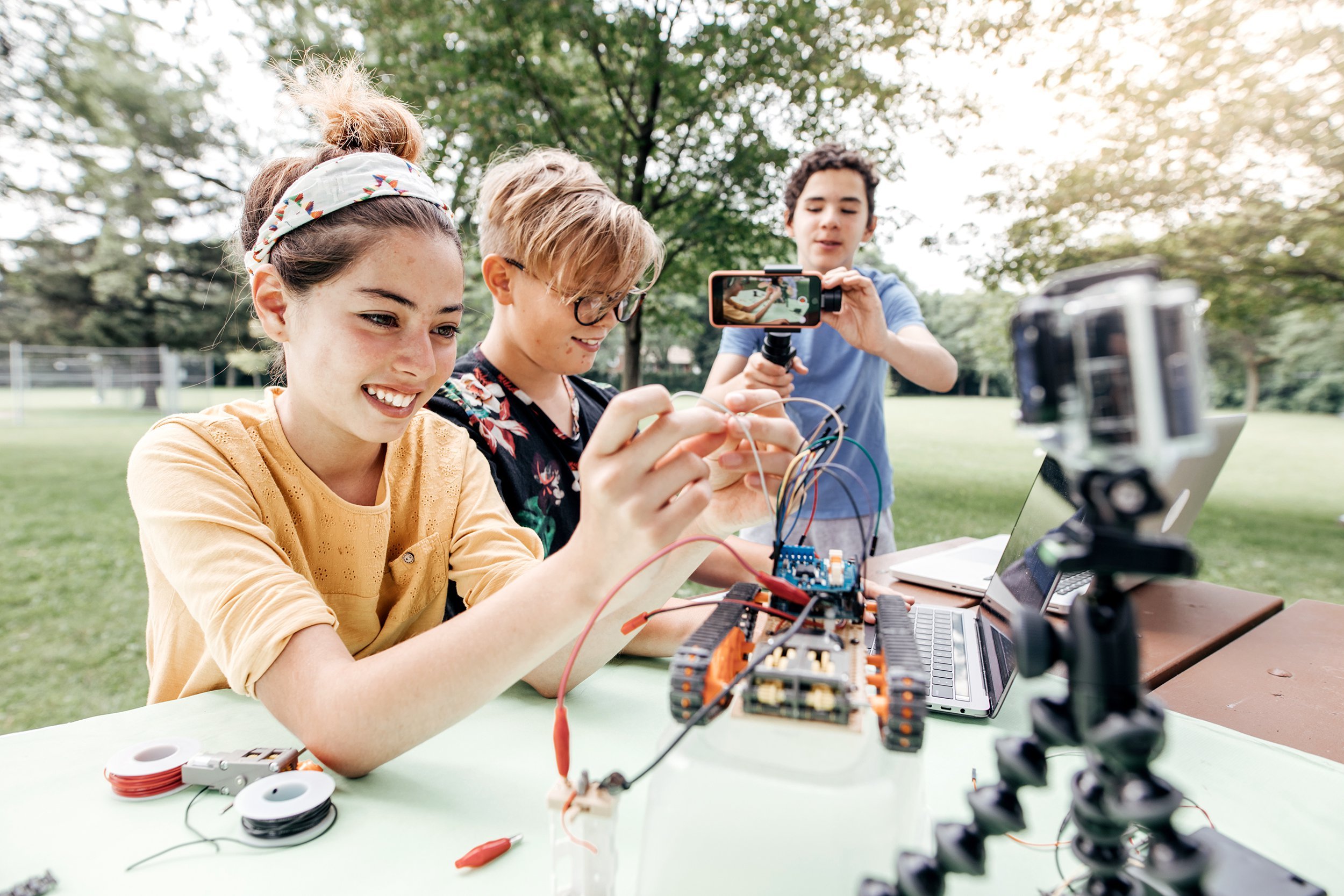 teens working on robotics project in park