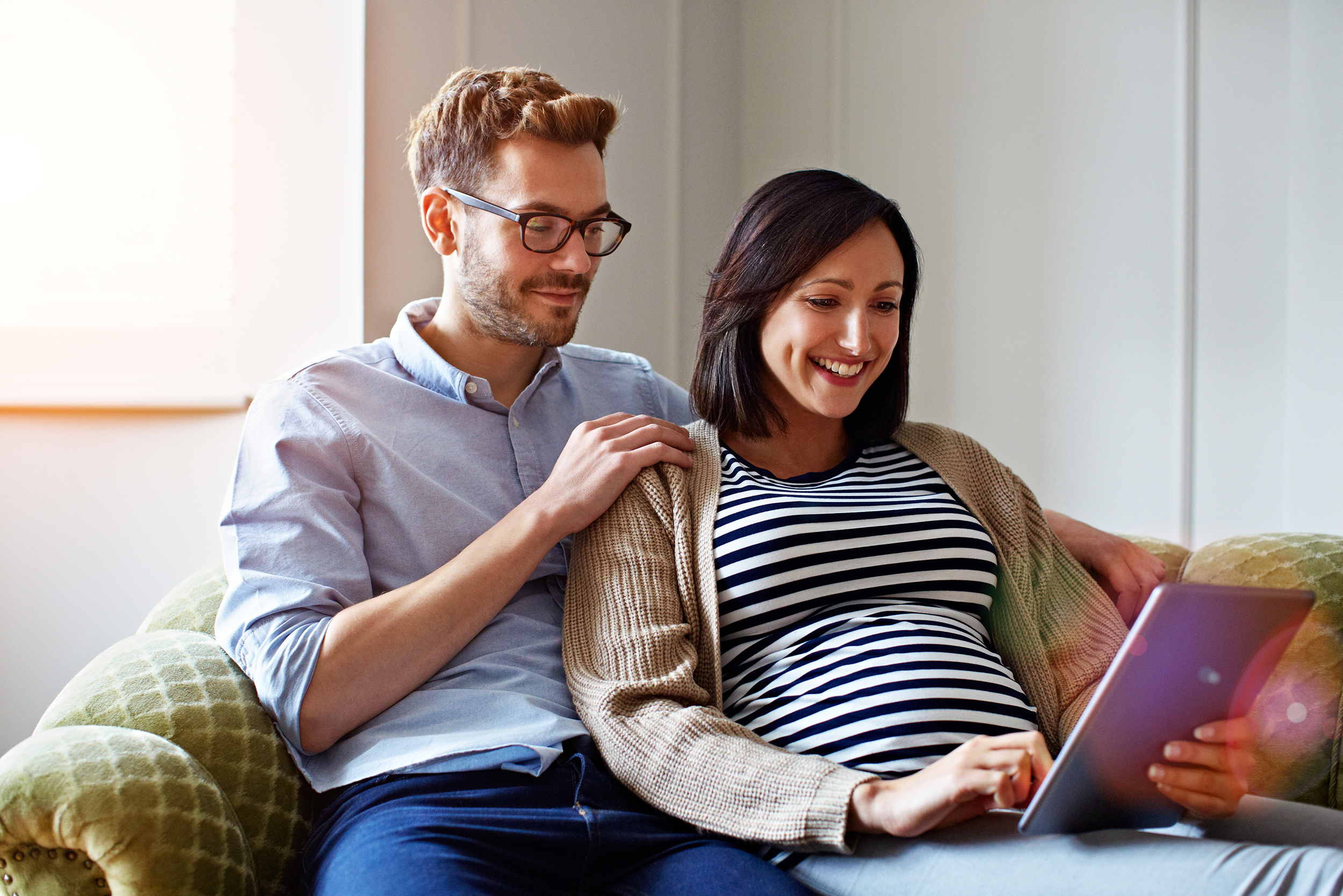 Pregnant woman and her husband researching on their laptop