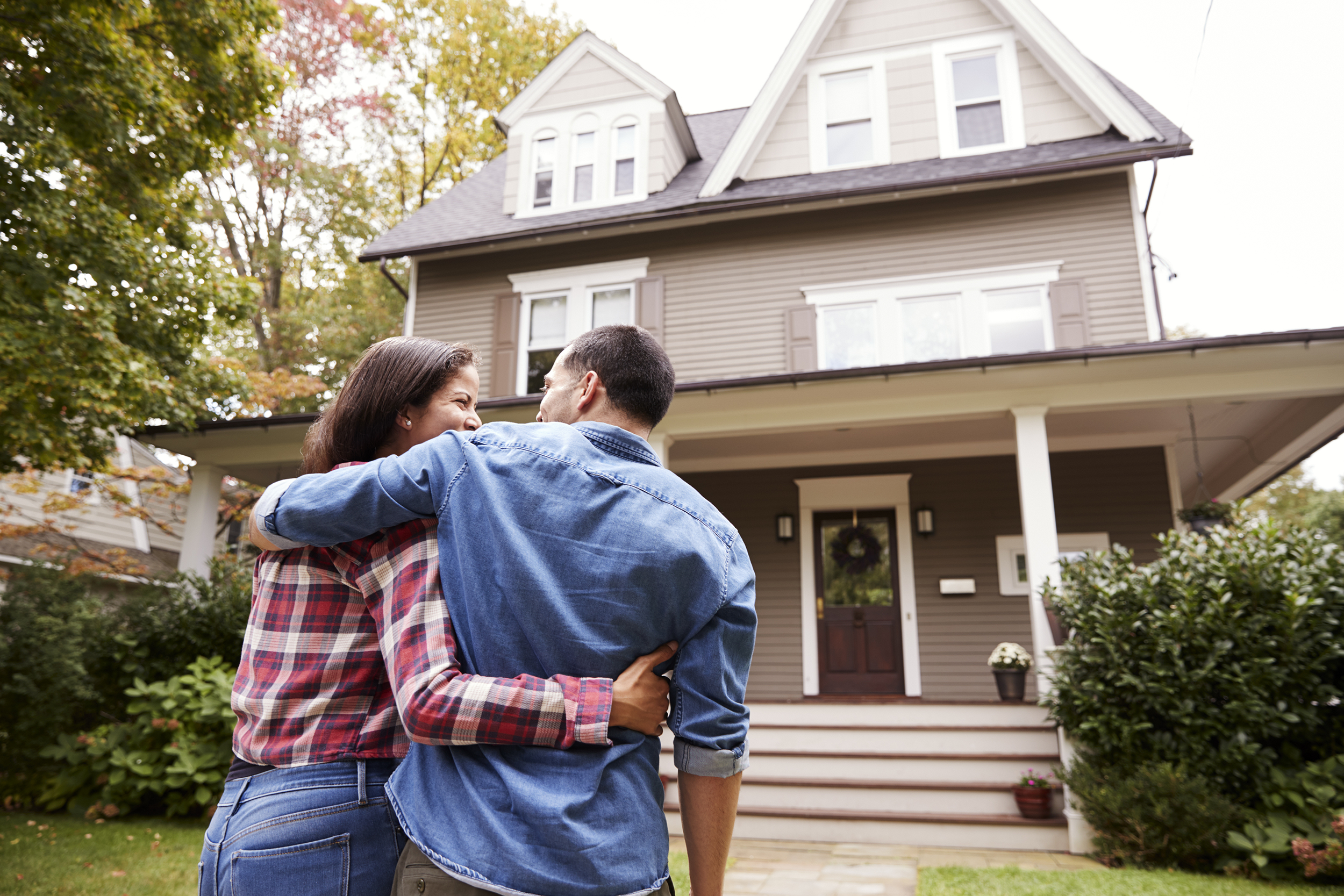 Happy couple hugging in front of their new home