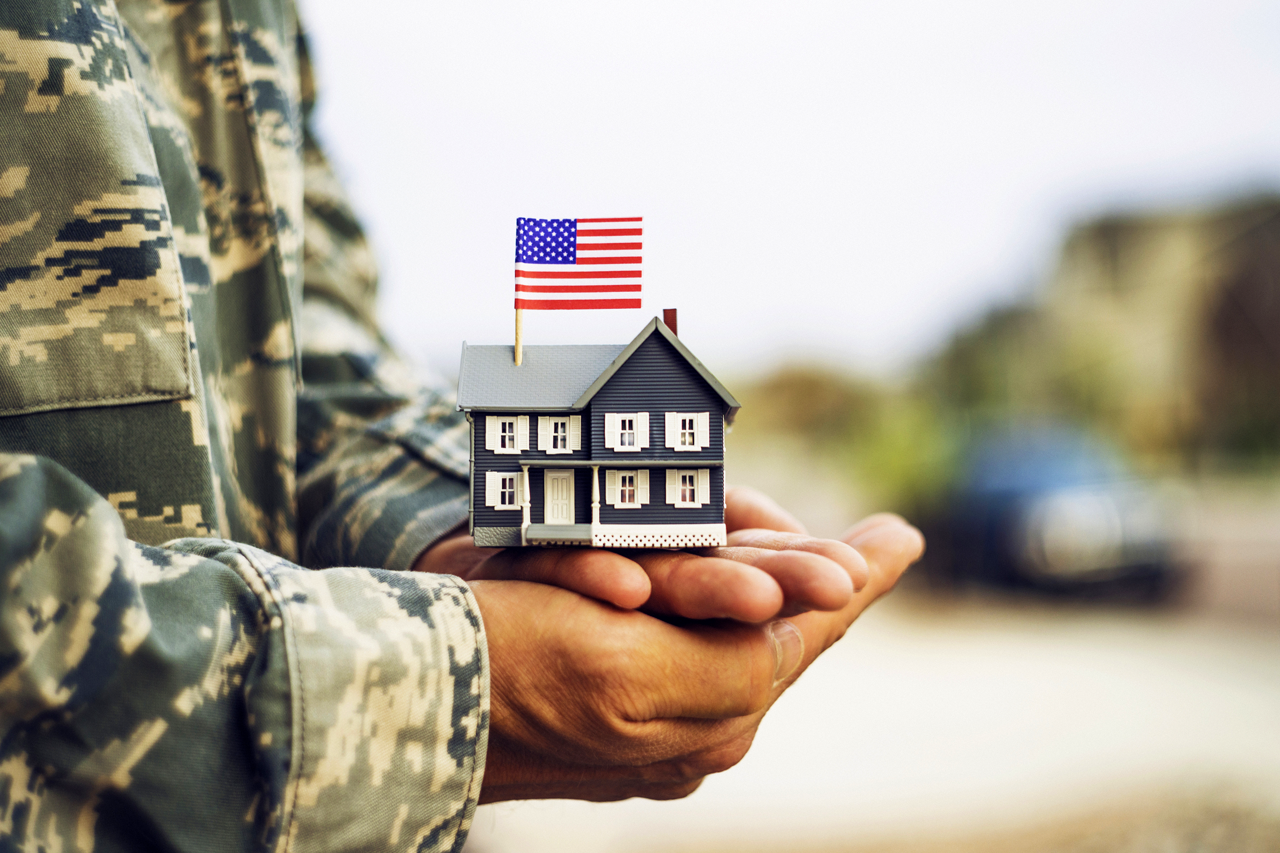 Veteran holding a small model home with an American flag