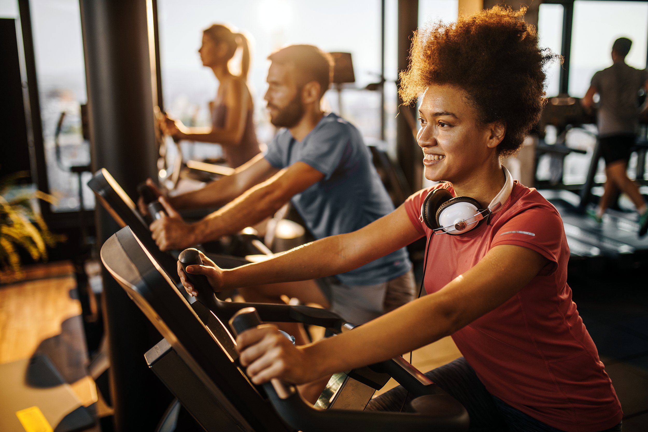 happy black athlete practicing on exercise bike in a health club