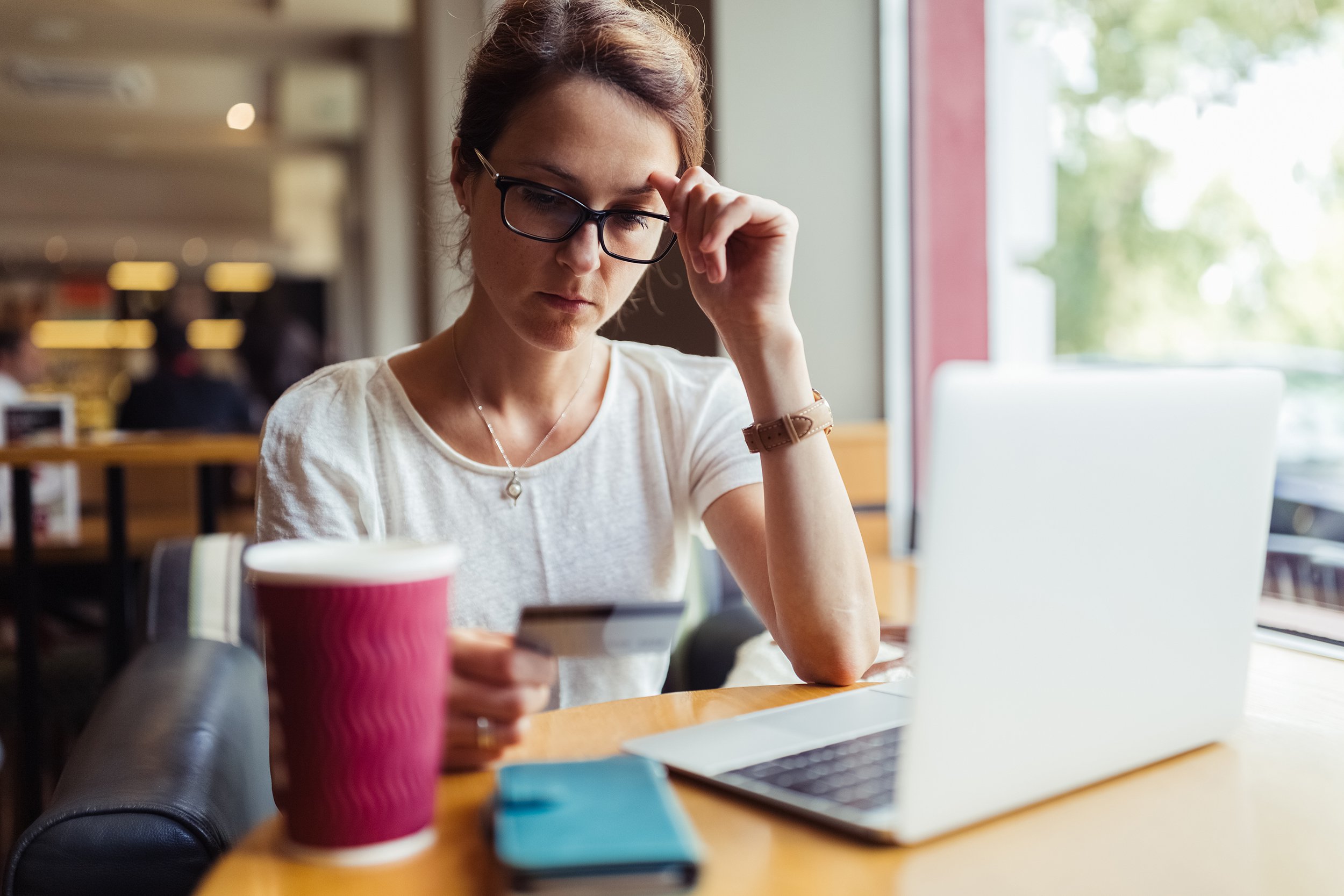 woman in cafe using credit card for online payments