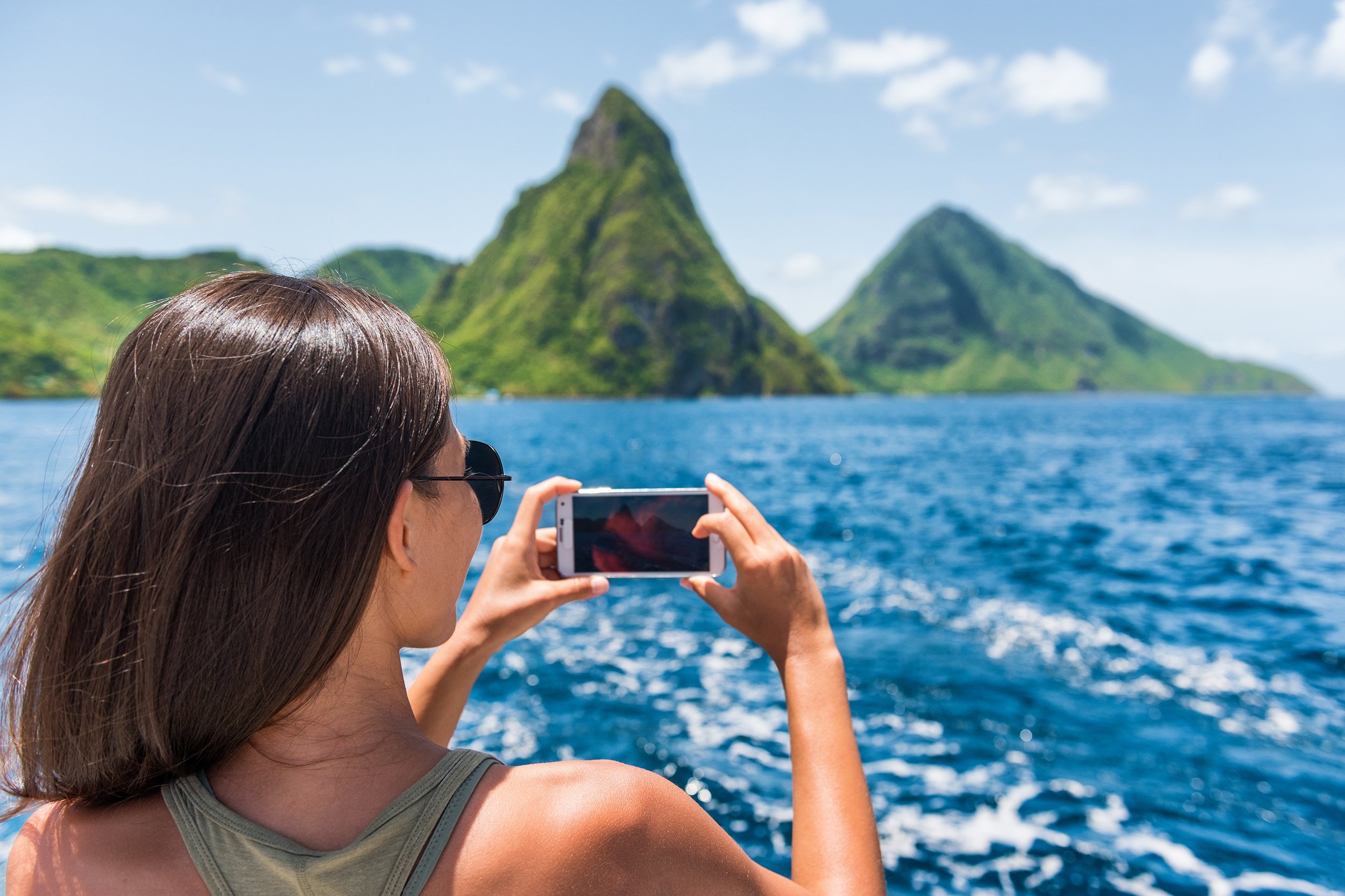 female tourist taking mobile phone pictures of Deux pitons peaks, St-Lucia, Caribbean