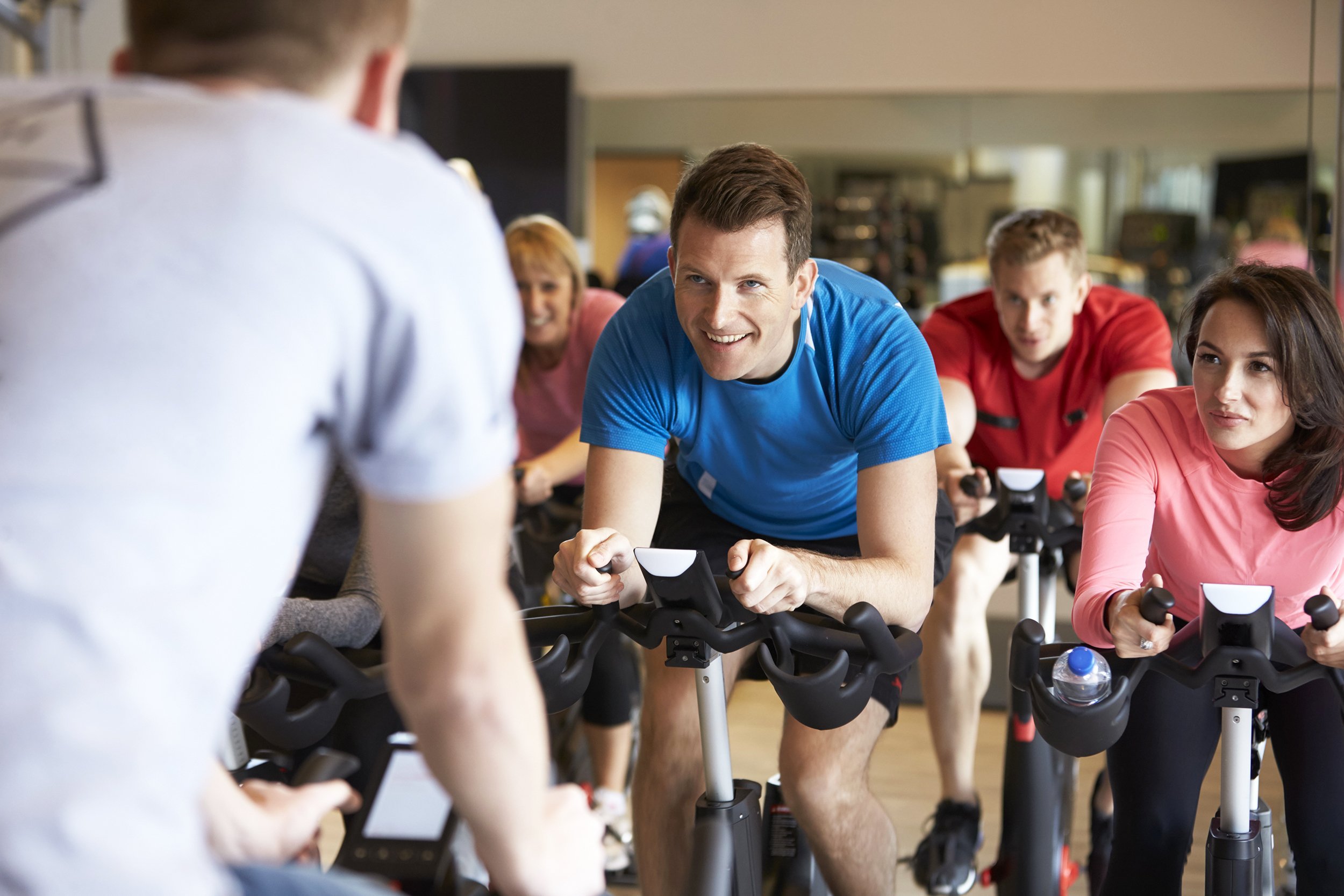 instructor in foreground with spinning class at a gym