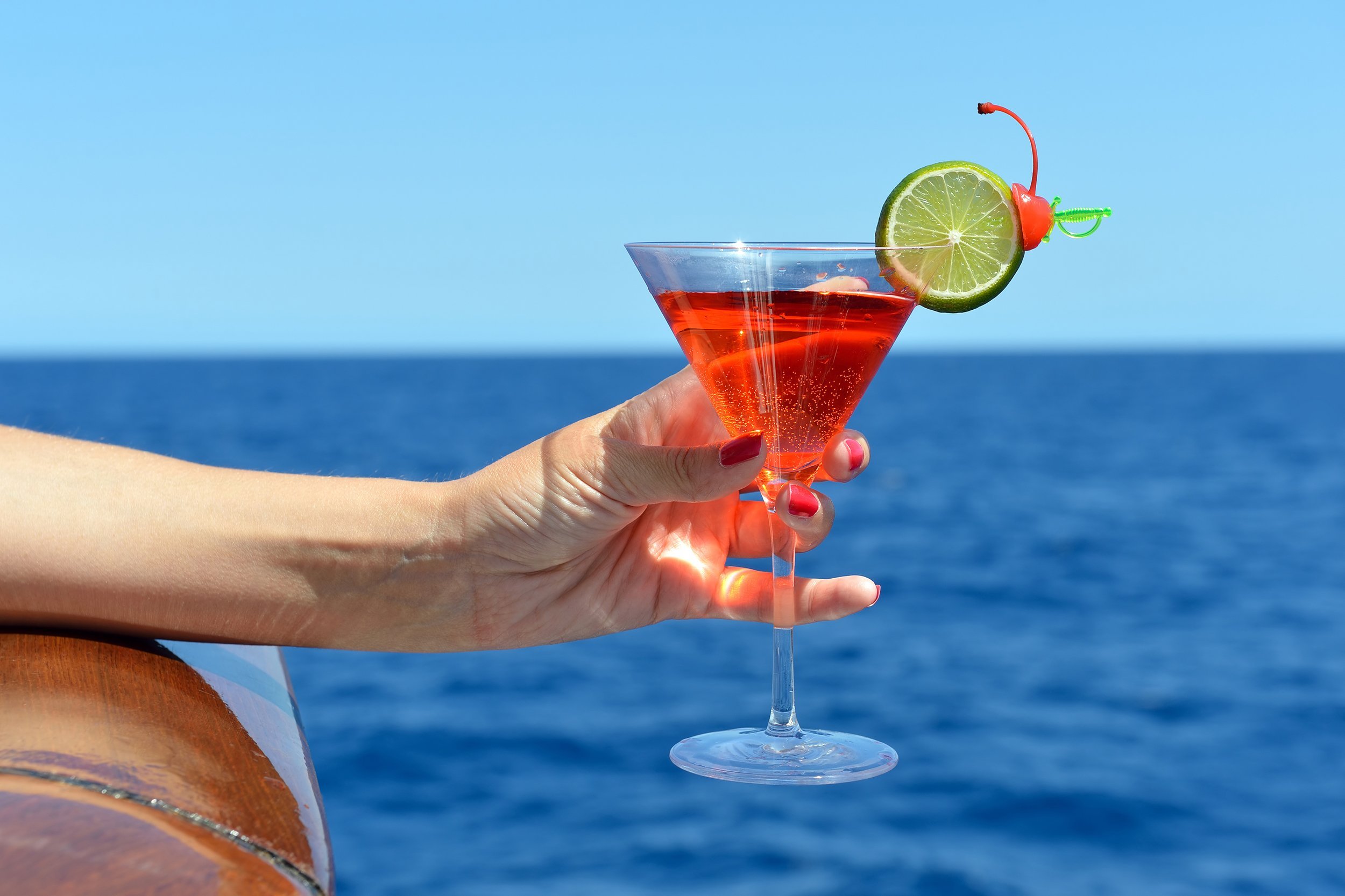 hand holding cocktail on cruise ship over the edge