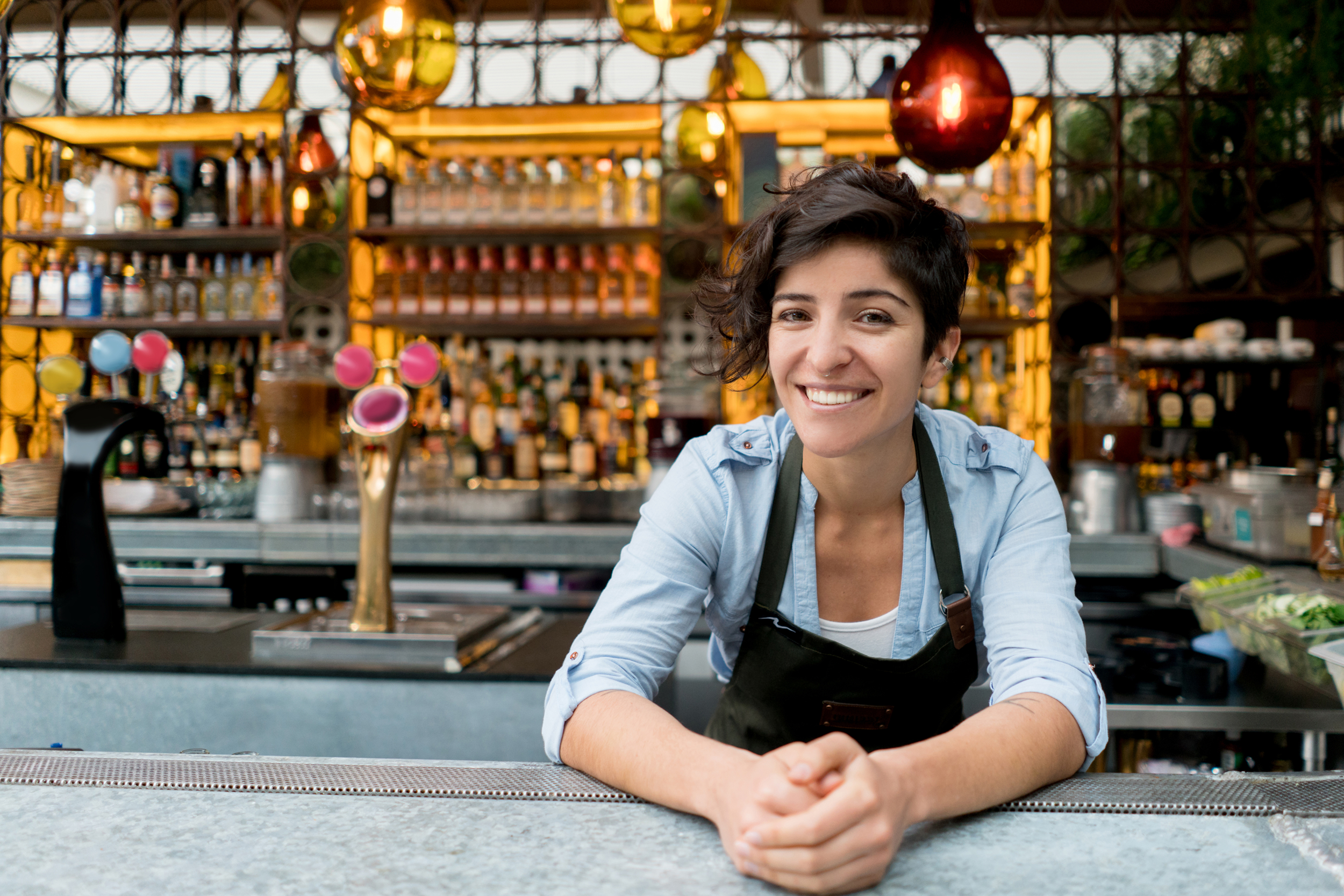 Happy female bartender leaving over the bar