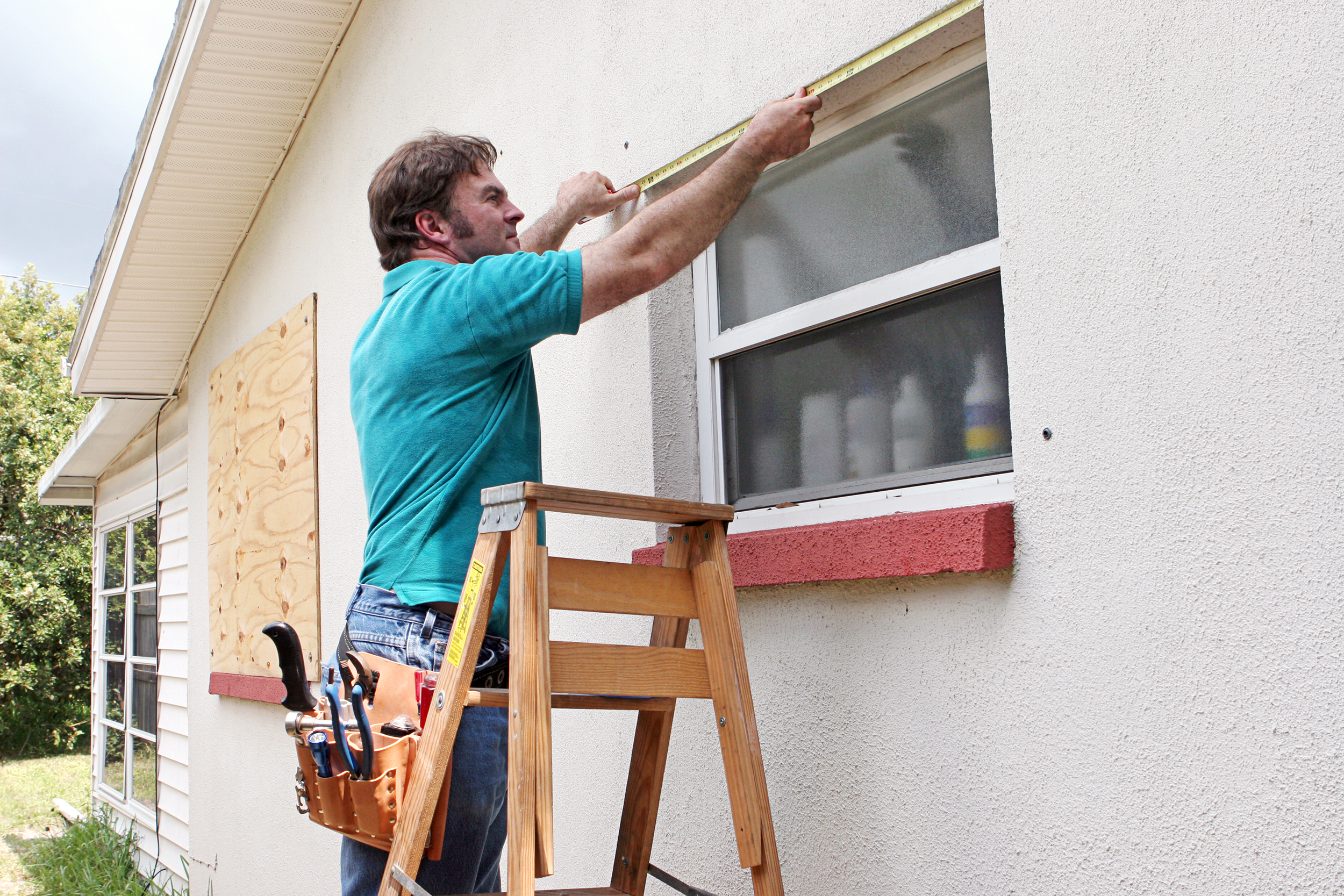 Repair man or caretaker boarding up windows on a house