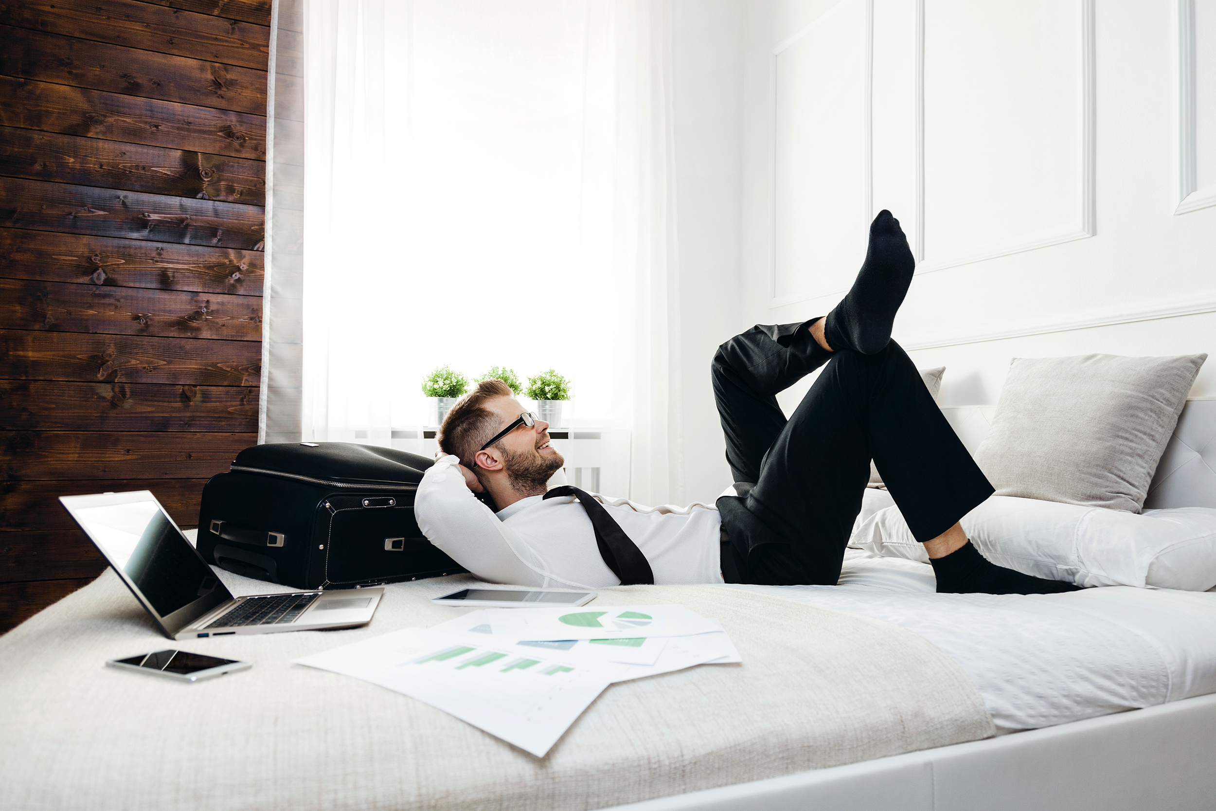 Happy business man lying on his hotel bed
