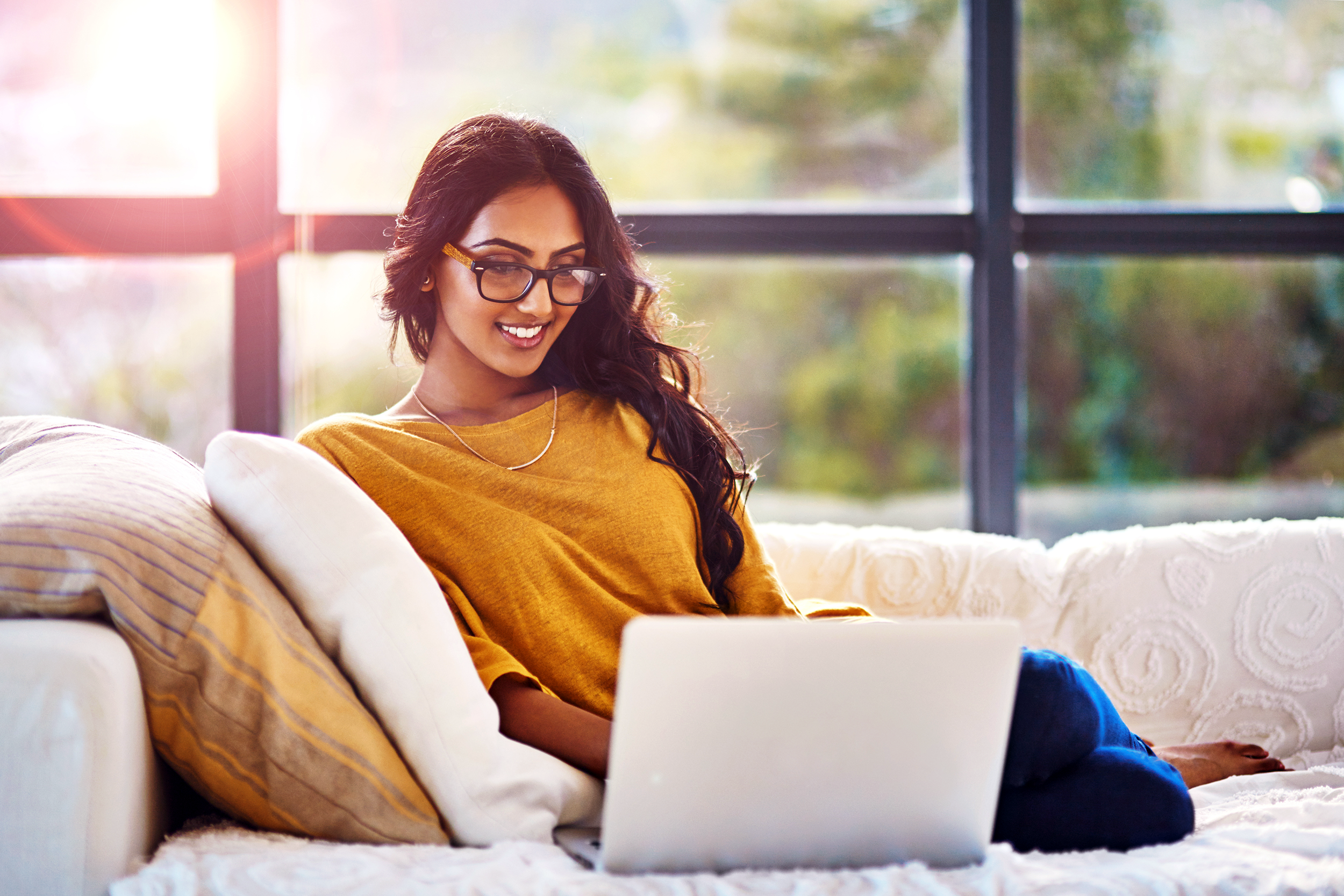 Happy woman working on her laptop on the couch