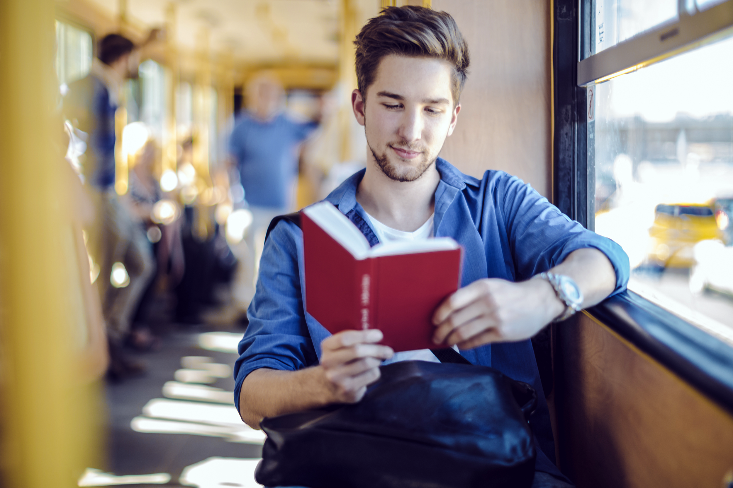 Man reading a book on the bus ride to work