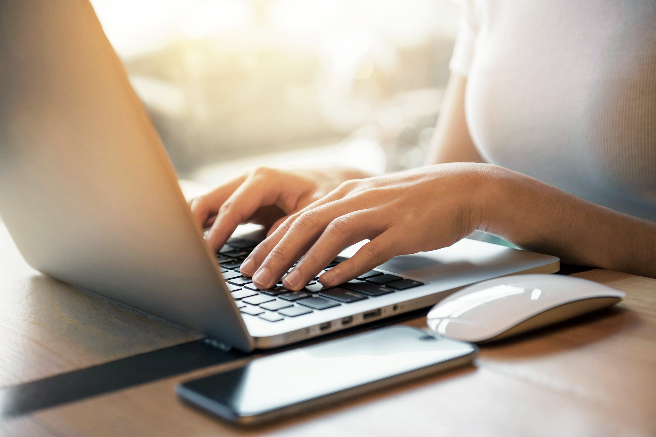 Closeup of woman's hands typing on laptop