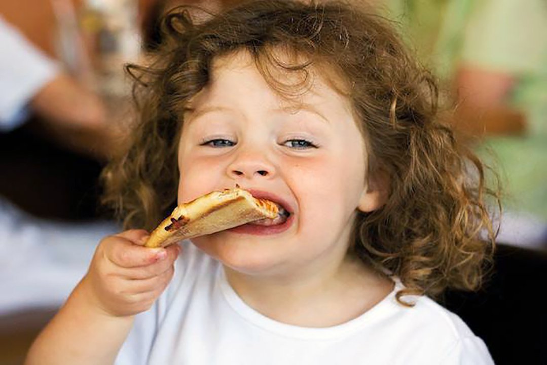 Kid eating a slice of pizza