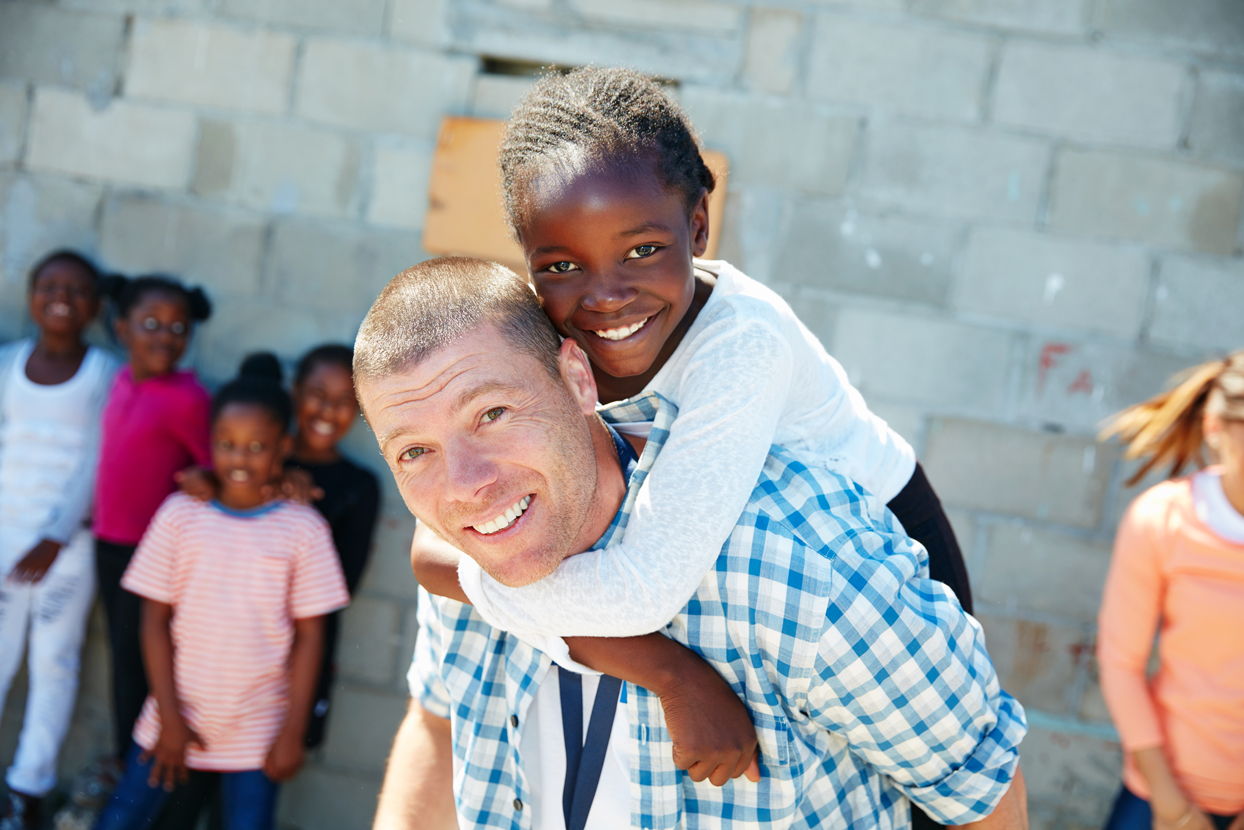 Happy American man assisting poor children in a foreign country