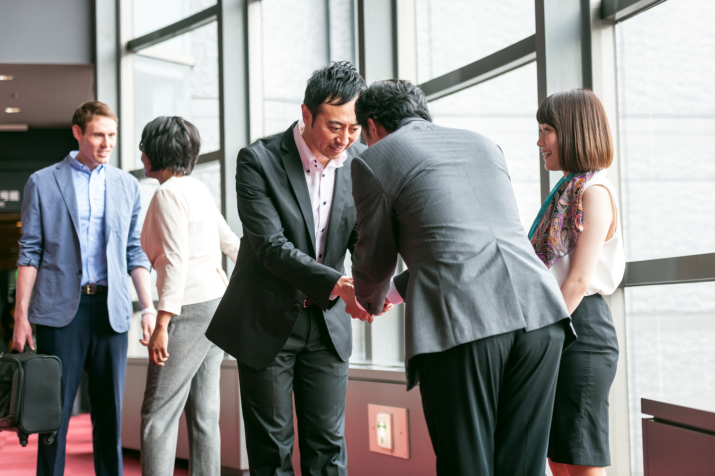 Business men bowing to each other in an Asian country with an interpreter standing next to them
