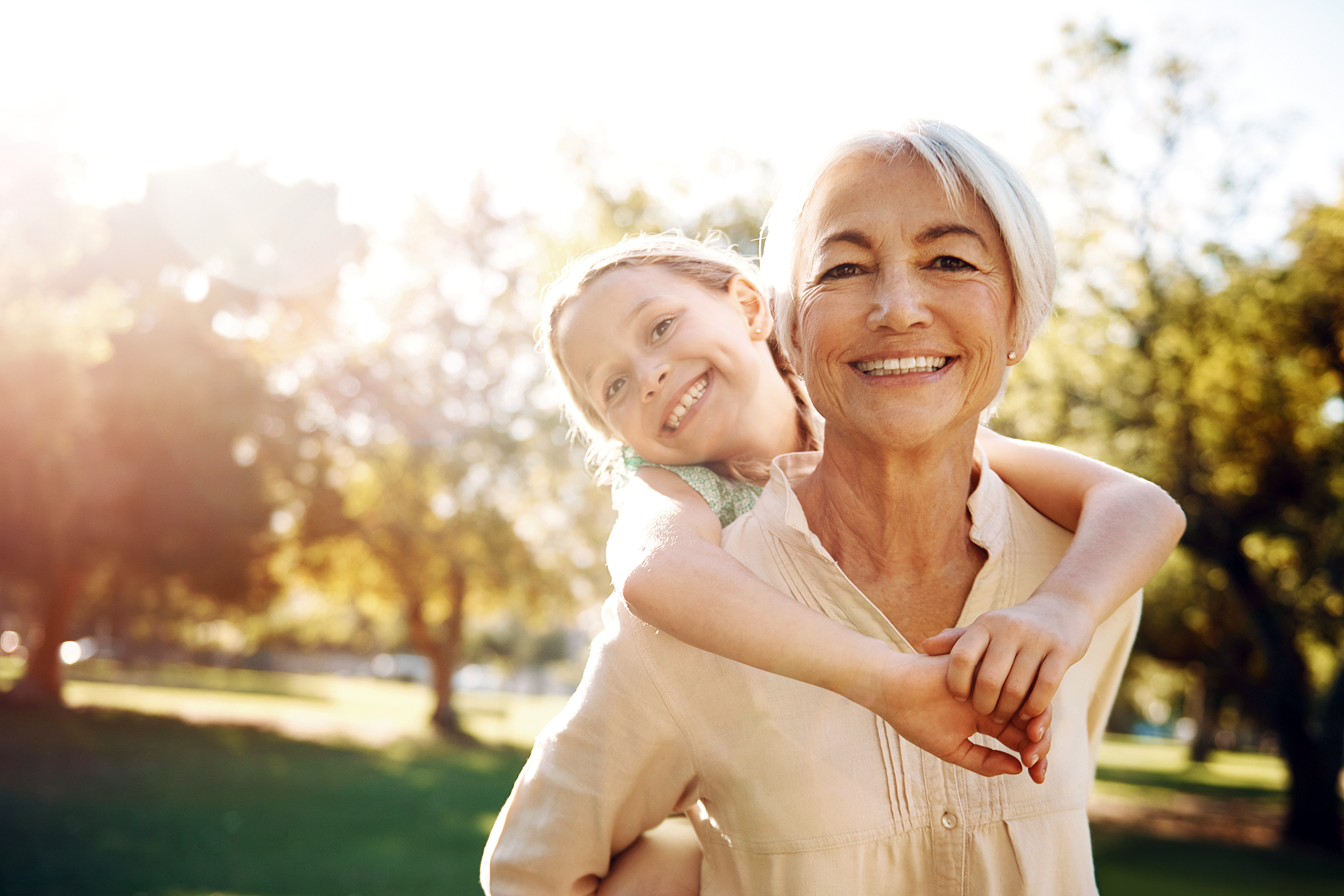 Grandmother carrying her granddaughter on her shoulders outside