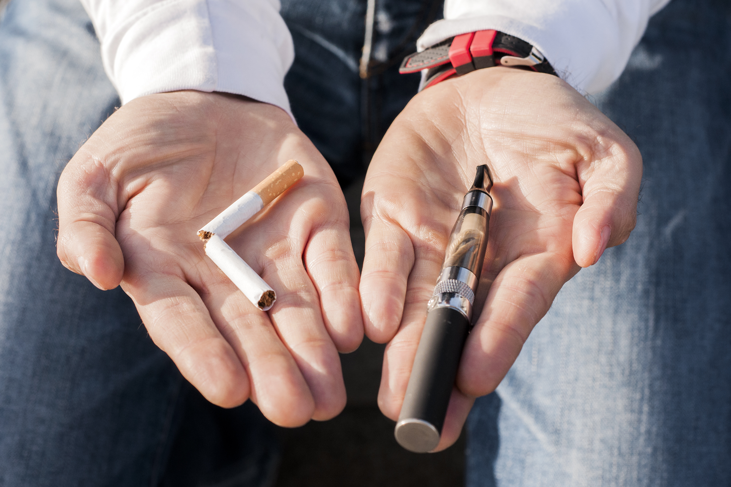Hand holding out a vaporizer and cigarette