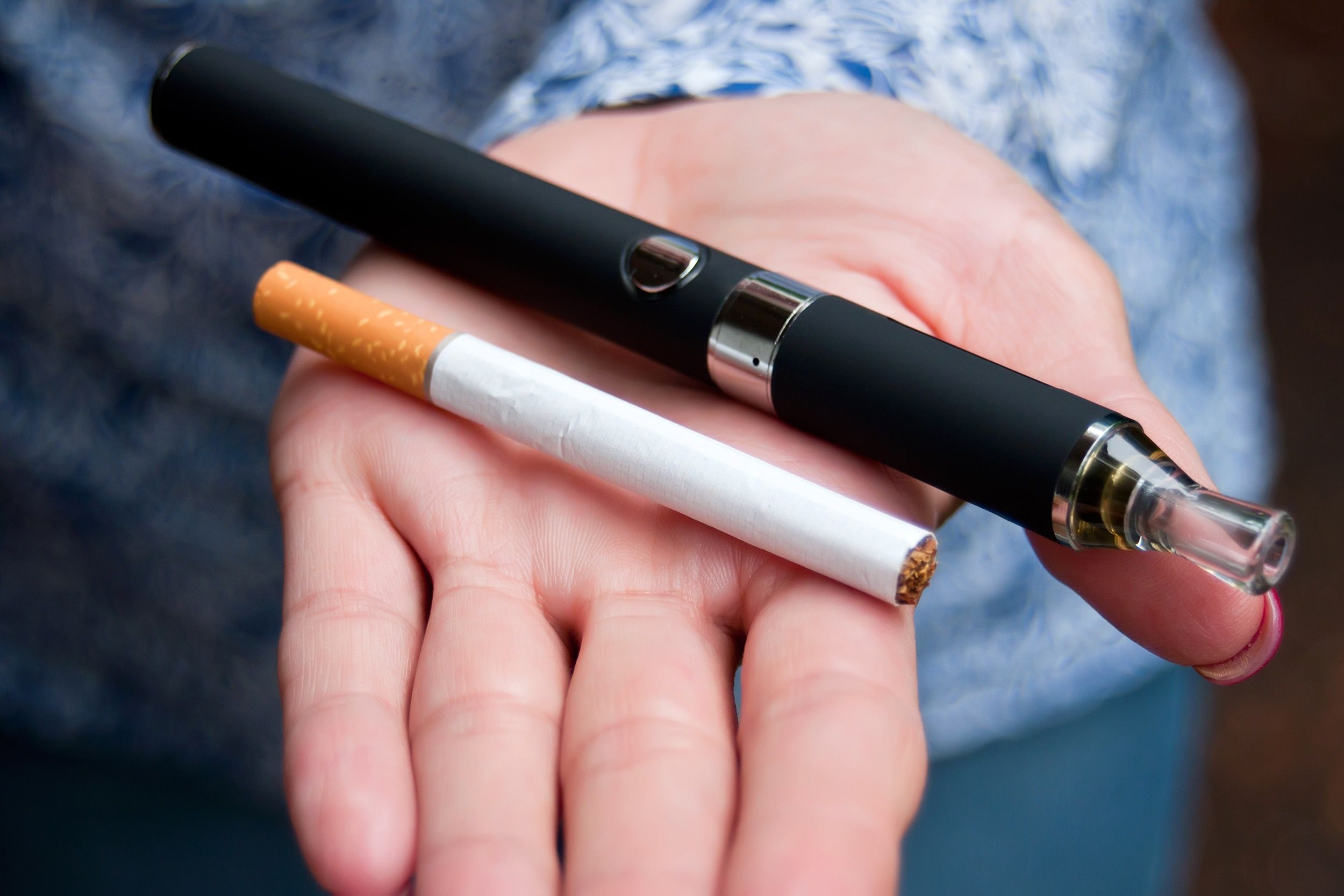 Hand holding a vaporizer and a cigarette
