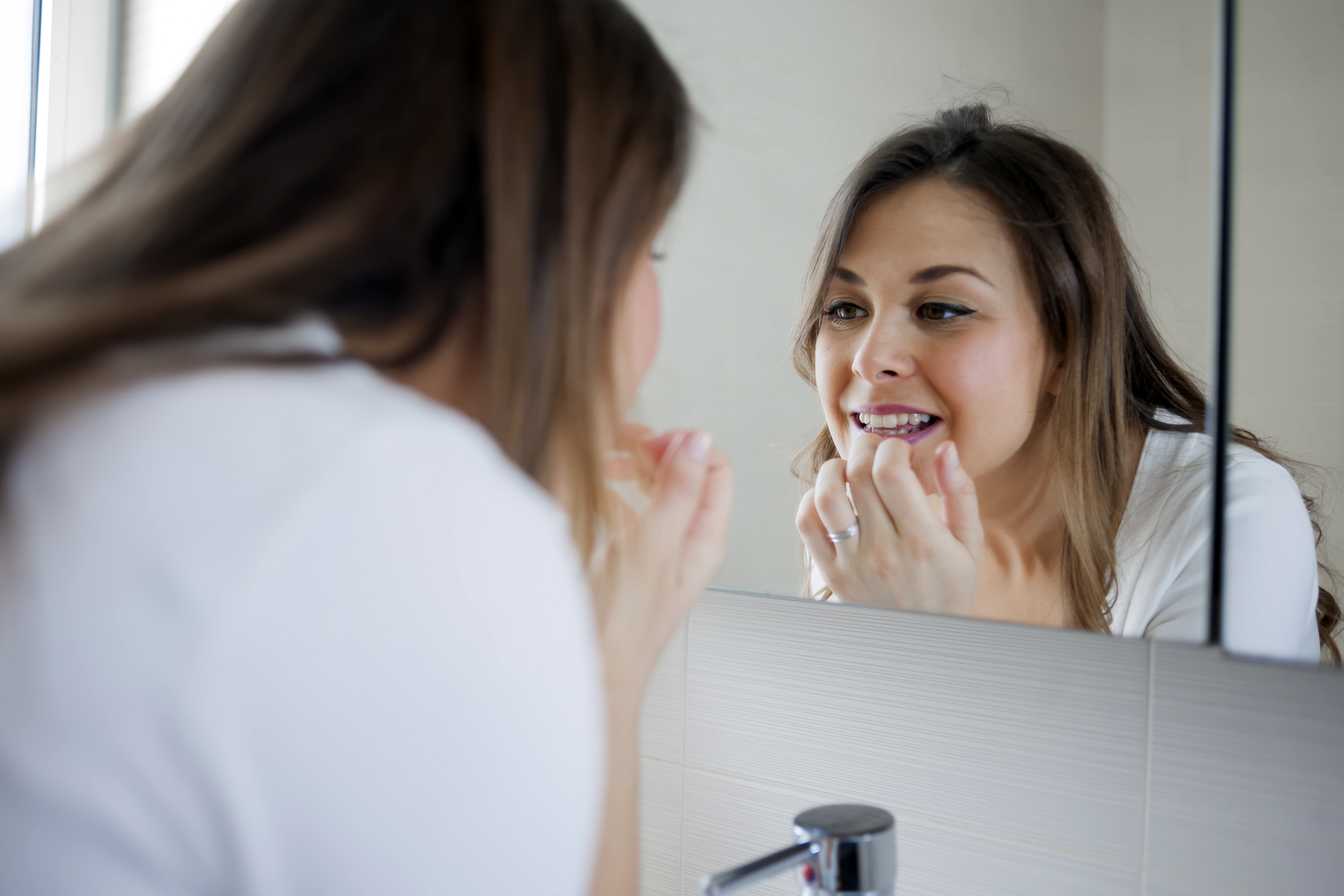 Woman checking her mouth in the mirror