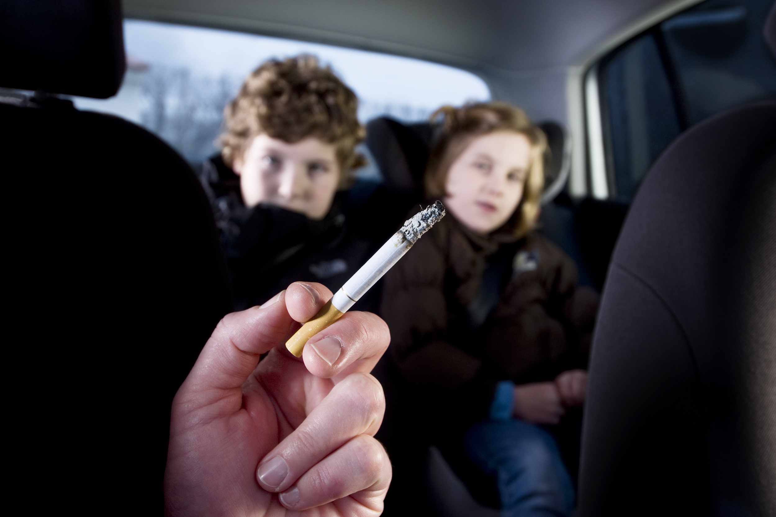 Parent smoking in the car with kids in the backseat